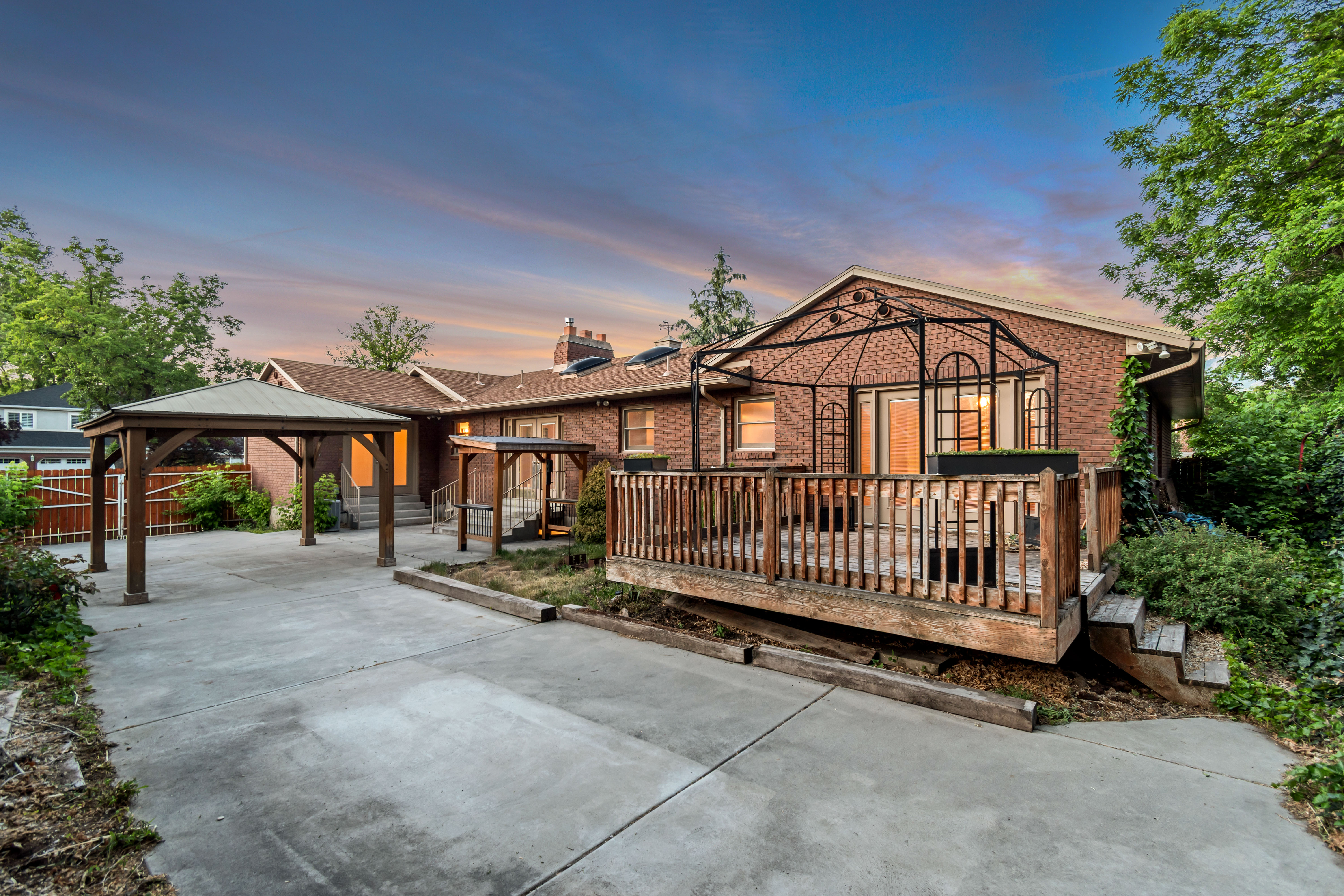 Brick exterior with a multi-level wood deck, an attached open-air gazebo, and a covered carport structure