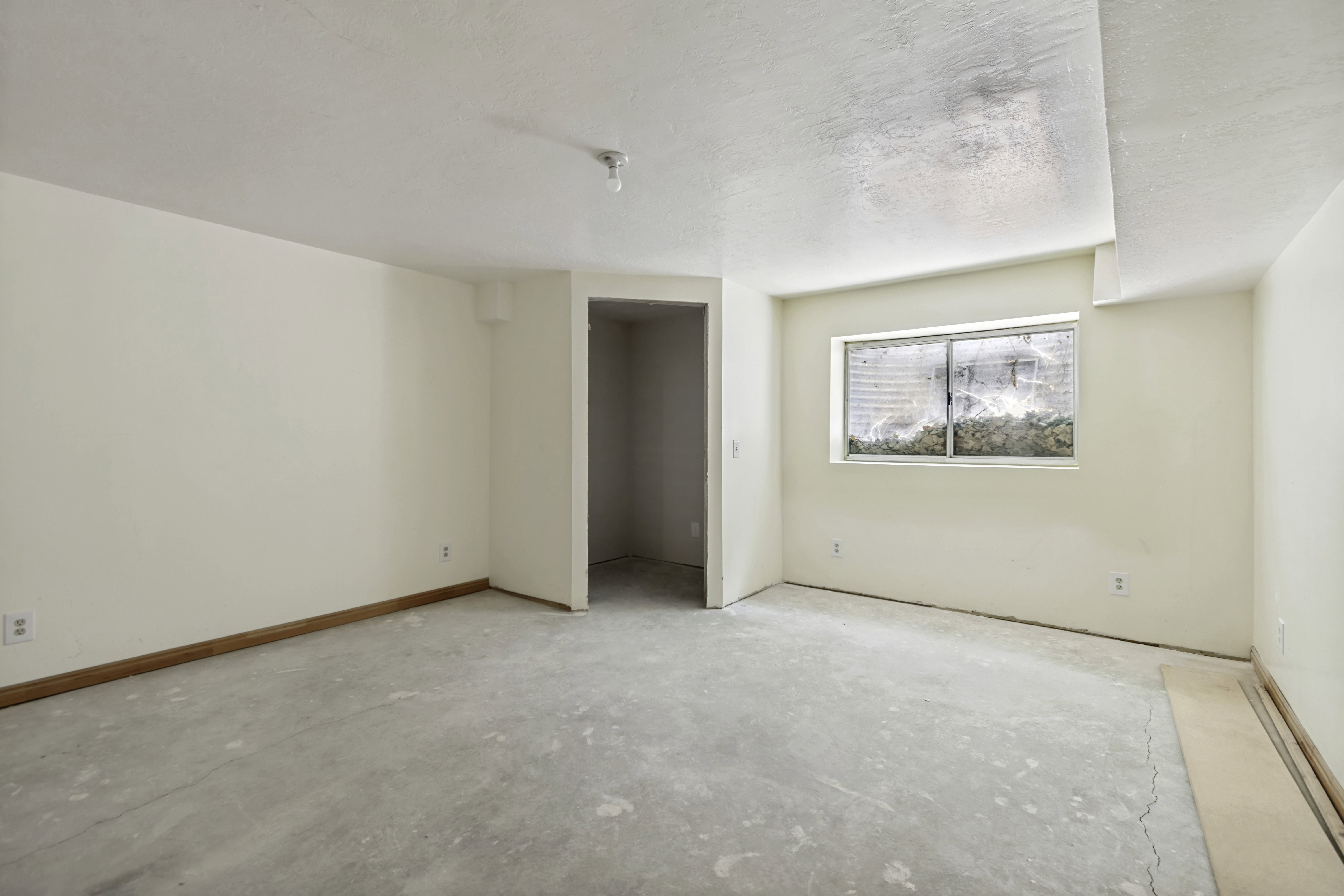 Spacious room featuring light-toned walls and a large window