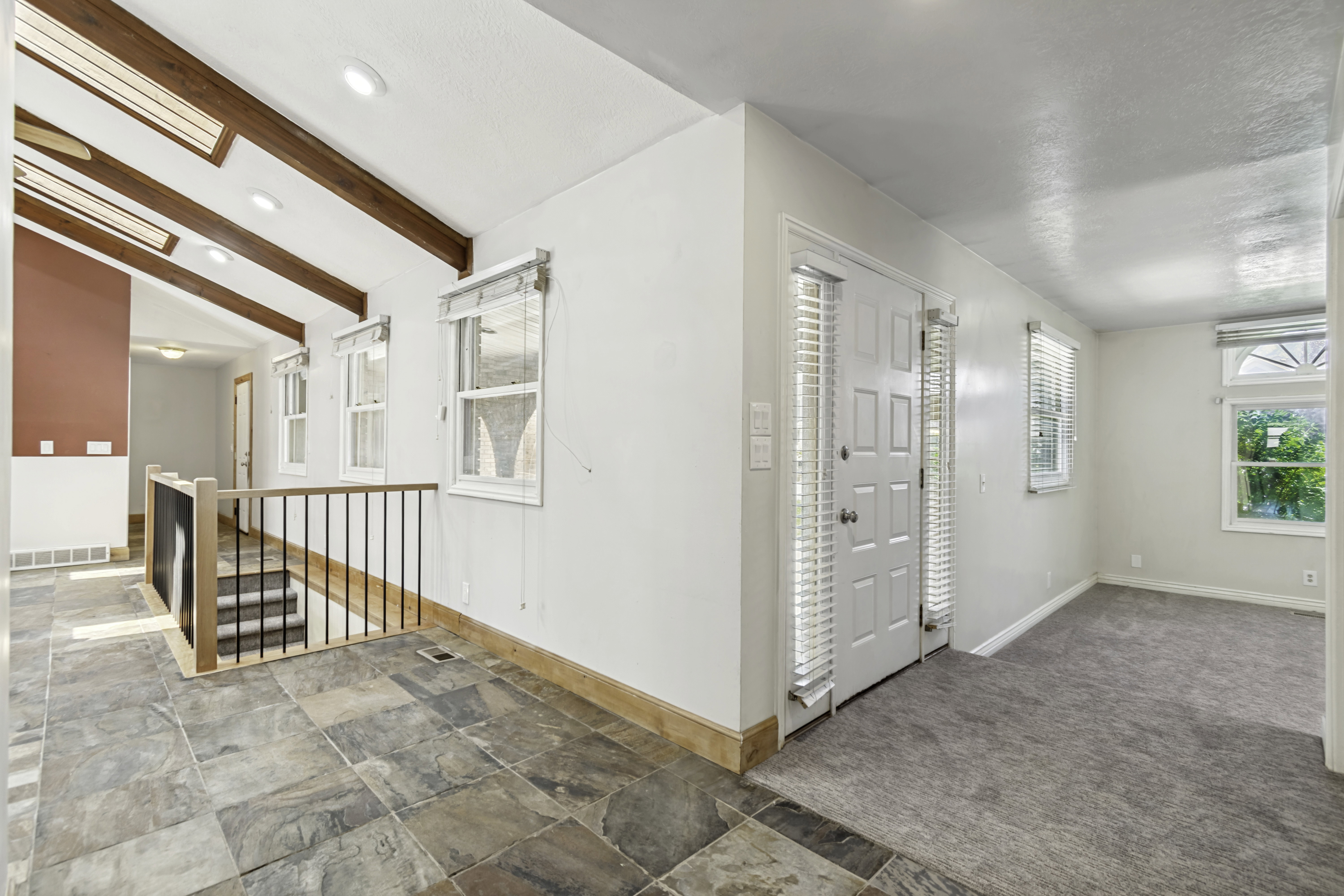 Foyer featuring natural stone flooring, exposed wood beam ceiling, recessed lighting, and a paneled entry door with sidelights