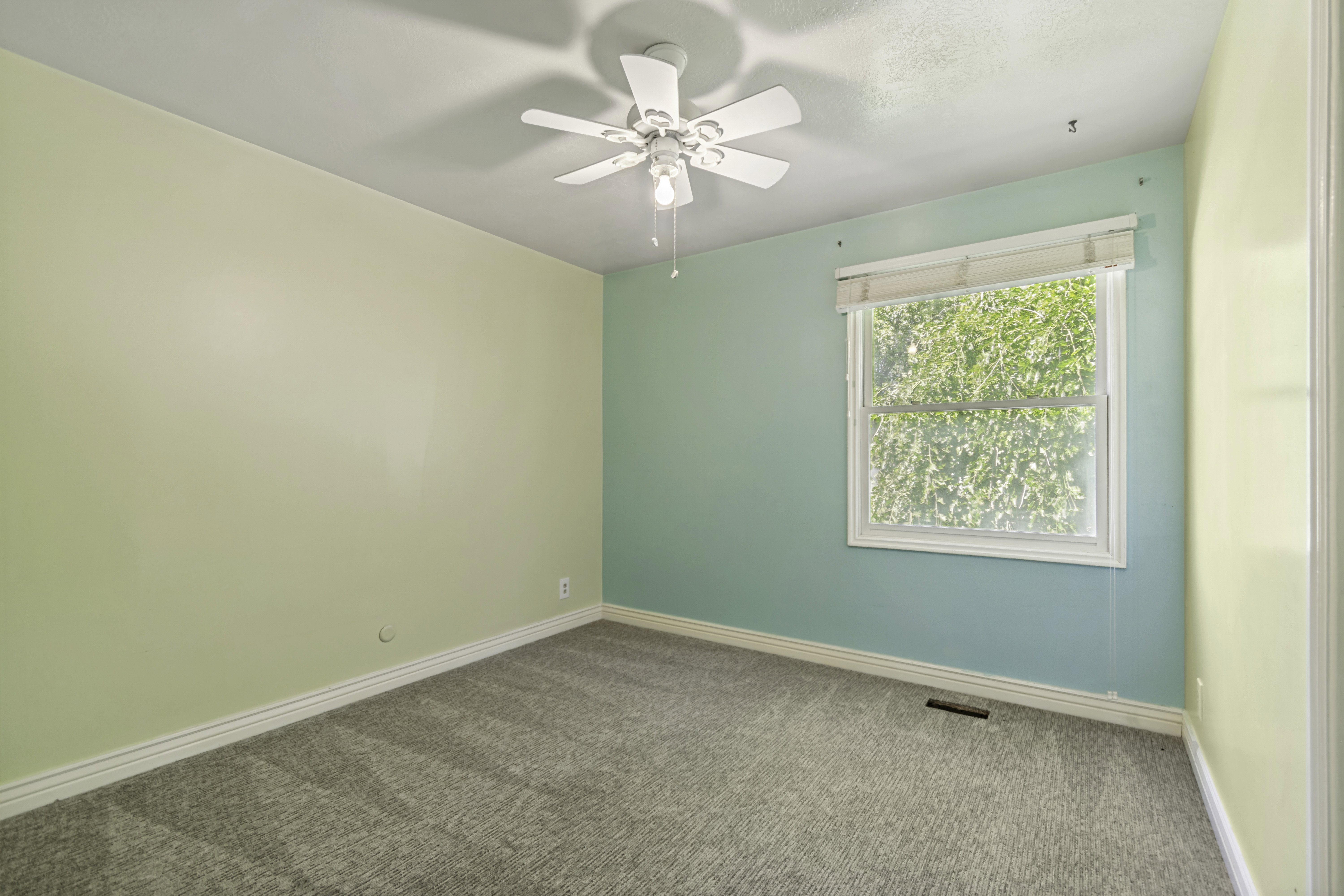 Carpeted room with a ceiling fan light fixture, white trim, and a window with a white frame