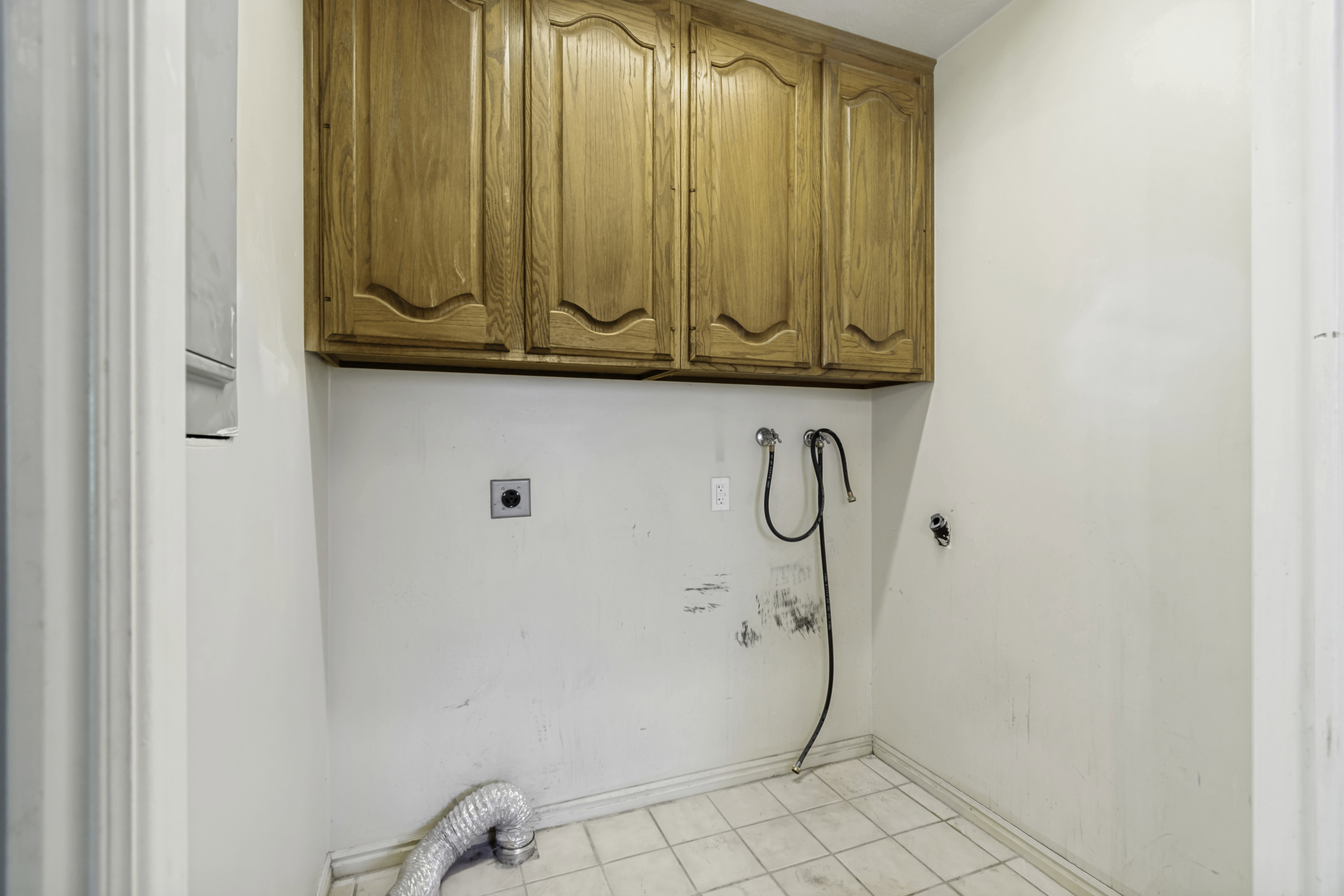 Utility space featuring upper wood cabinetry and tile flooring