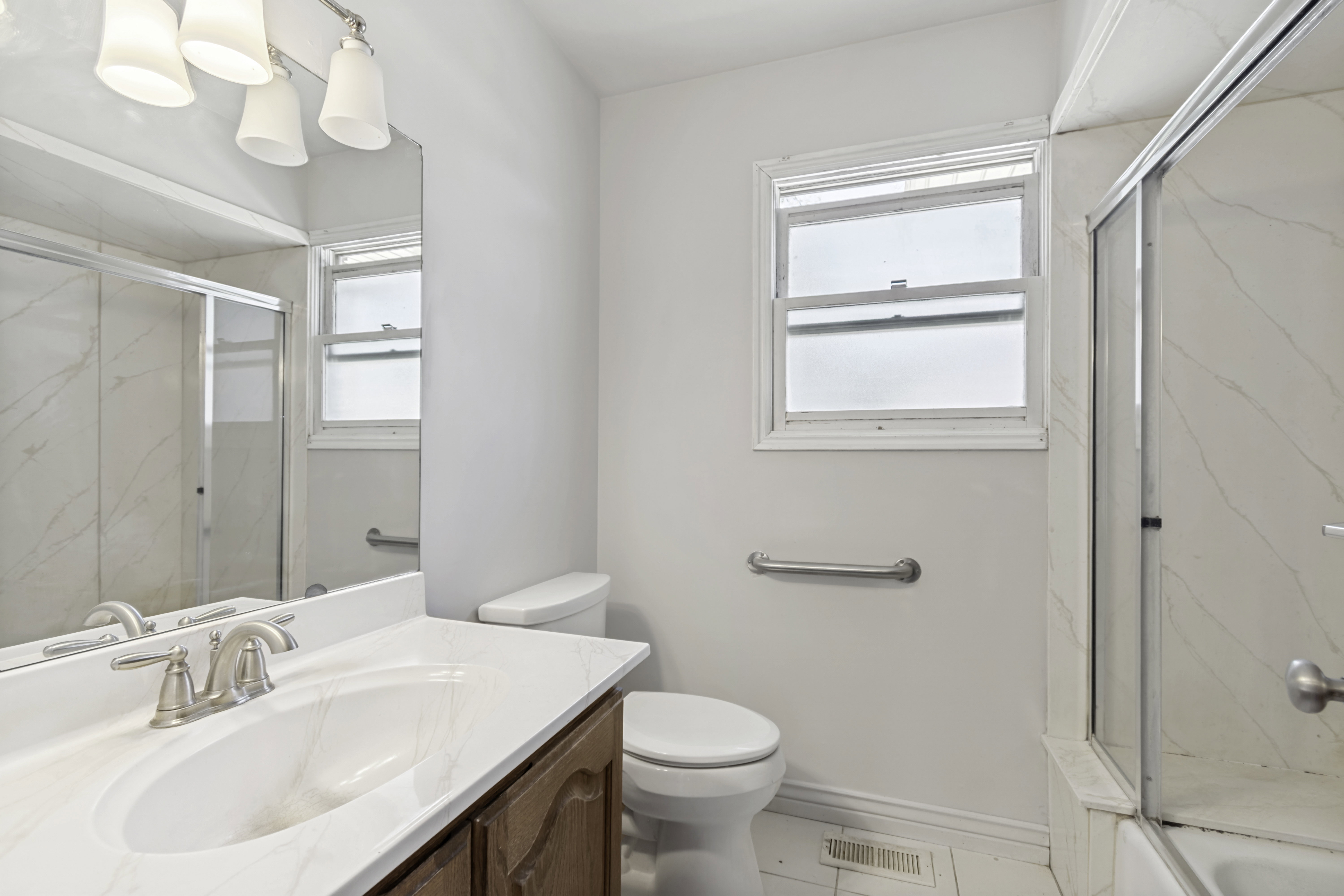 Bathroom featuring a wood-finish vanity with a white countertop and integrated sink, brushed nickel faucet, and a large wall-mounted mirror
