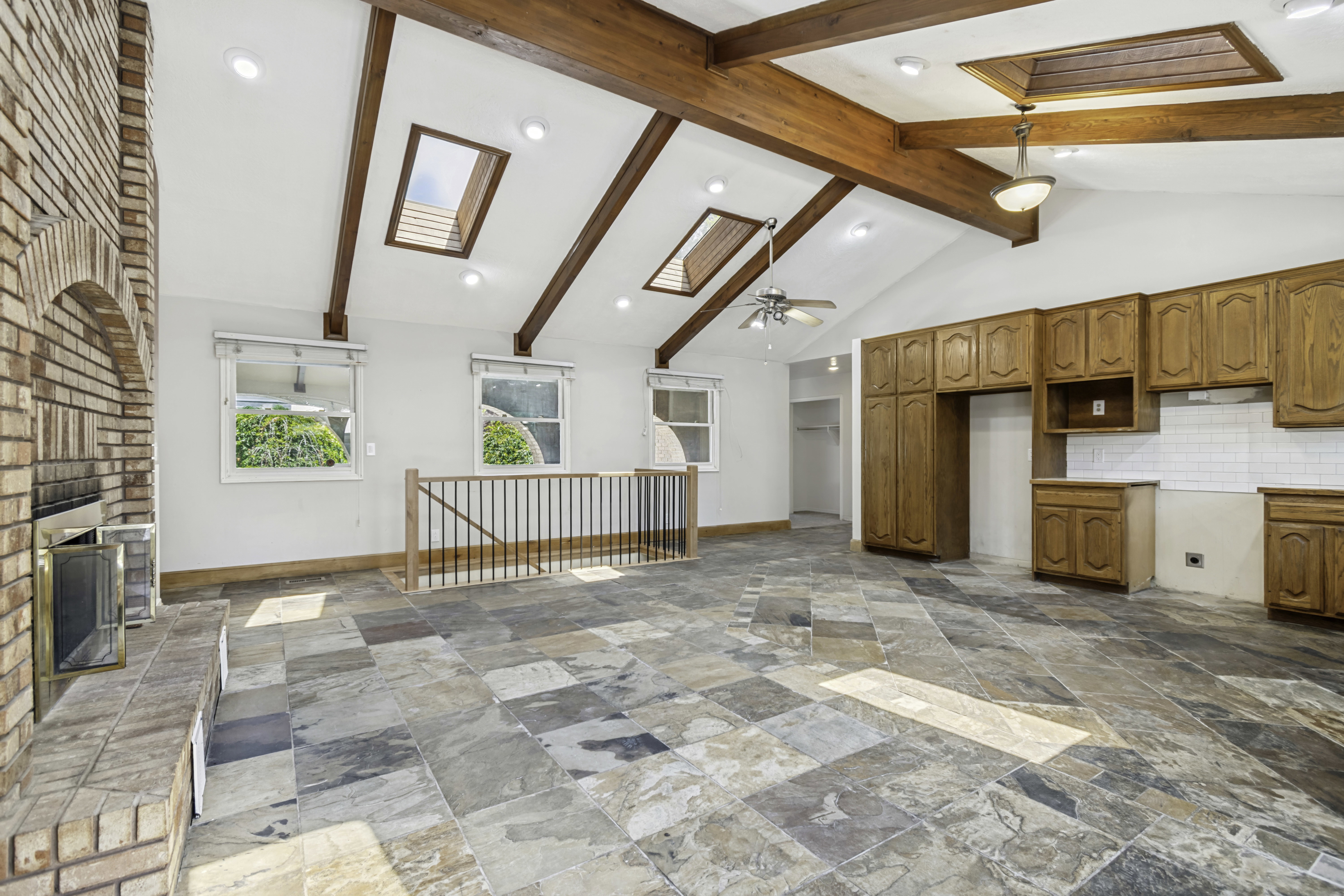 Vaulted white ceilings featuring exposed wood beams and multiple skylights