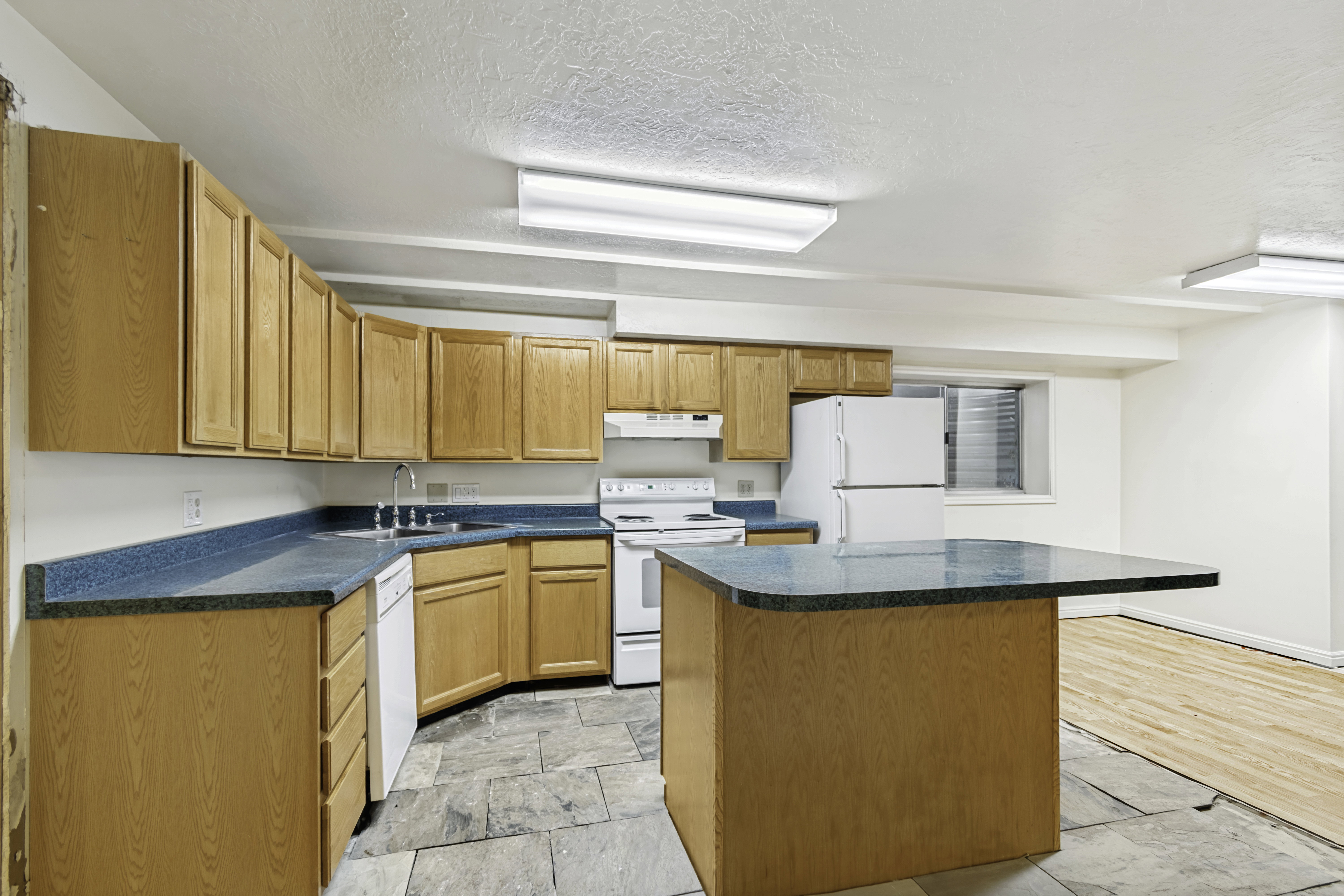 Kitchen featuring light wood-finish cabinetry, blue countertops, and white appliances