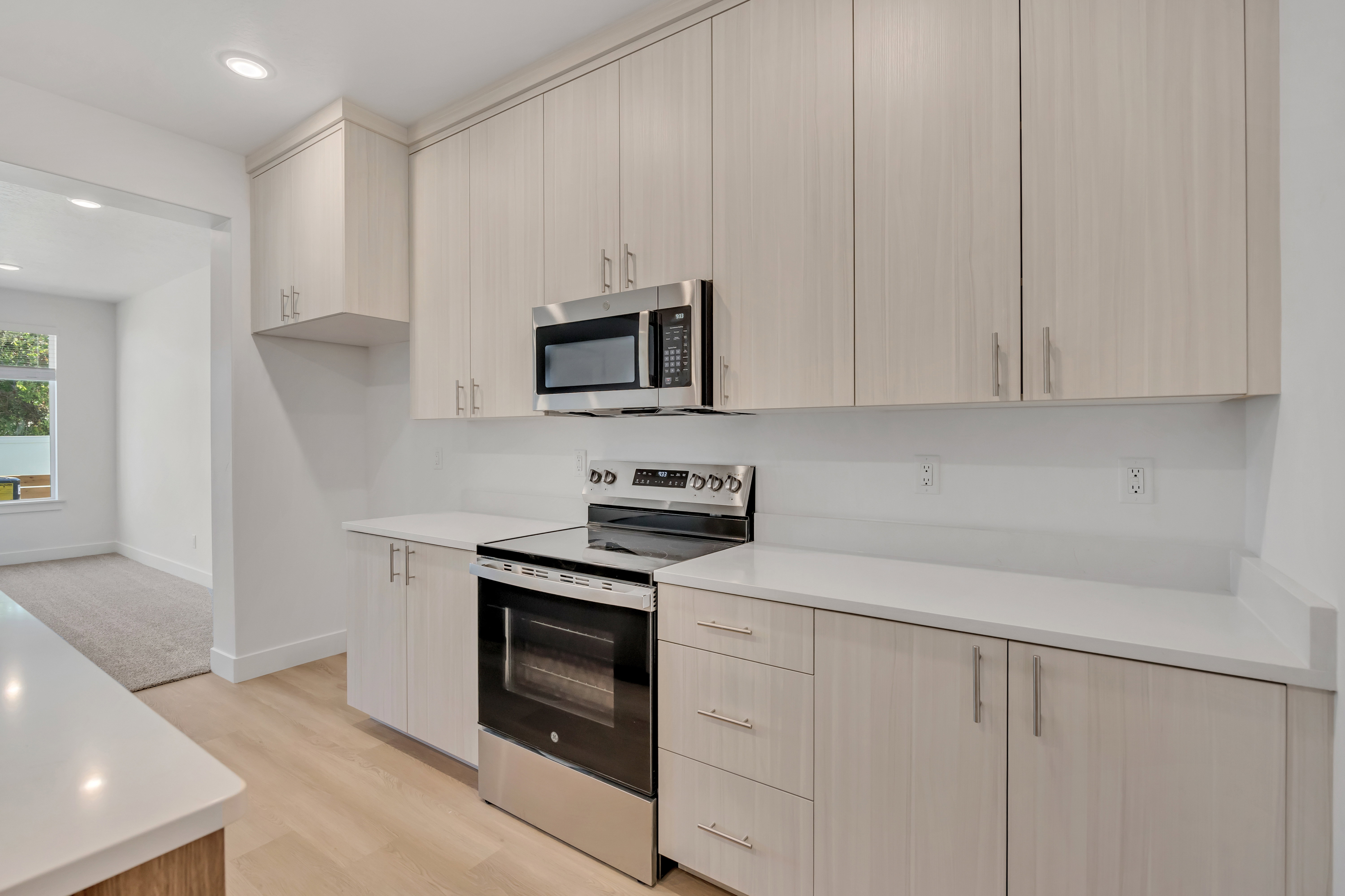 Contemporary kitchen featuring light wood-finish cabinetry, stainless steel appliances, white countertops, and recessed lighting