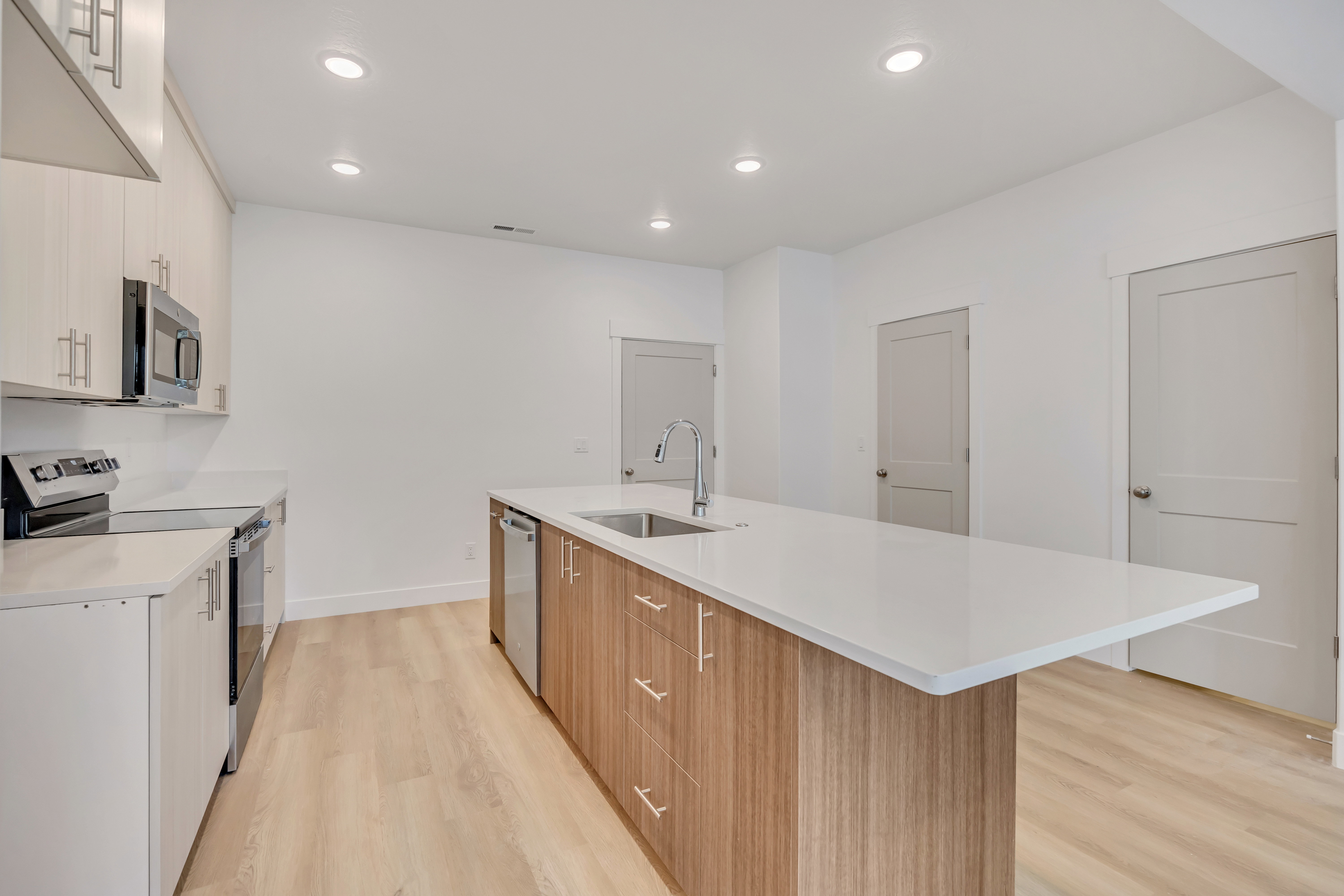 Modern kitchen featuring an expansive center island with an undermount sink and a waterfall-edge countertop