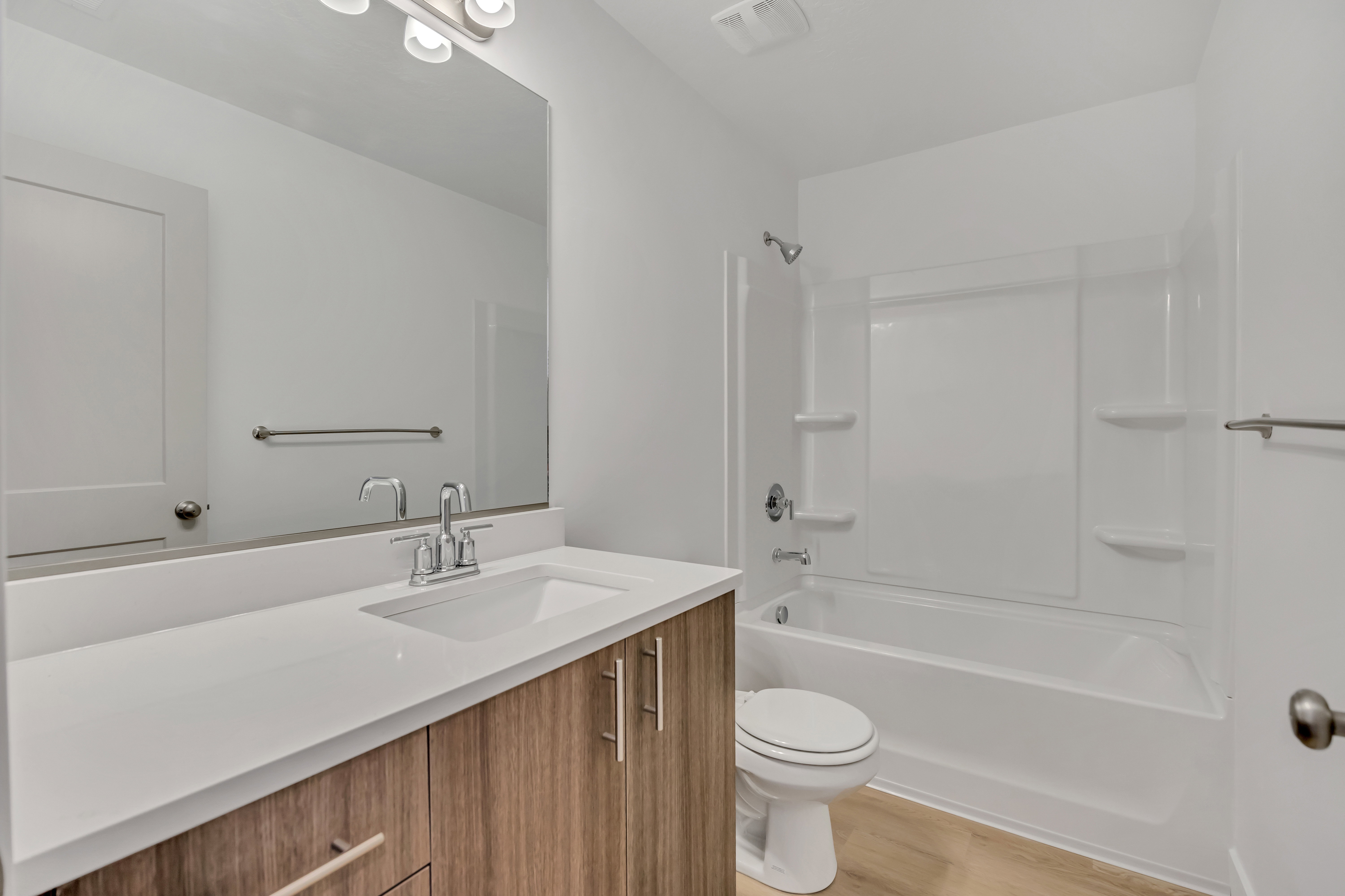 Bathroom featuring a vanity with a white countertop, under-mount sink, and wood-finish cabinetry