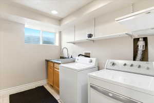 Dedicated laundry area featuring a utility sink, wood-finish cabinetry, and overhead shelving