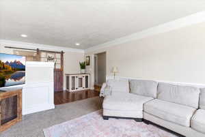 Living space featuring an accent barn door, recessed lighting, crown molding, and wood-finish flooring