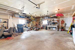 Spacious garage featuring a concrete floor, exposed ceiling joists, and multiple windows