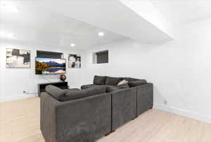 Bright living space featuring recessed lighting, light wood-finish flooring, white walls, and a visible support beam