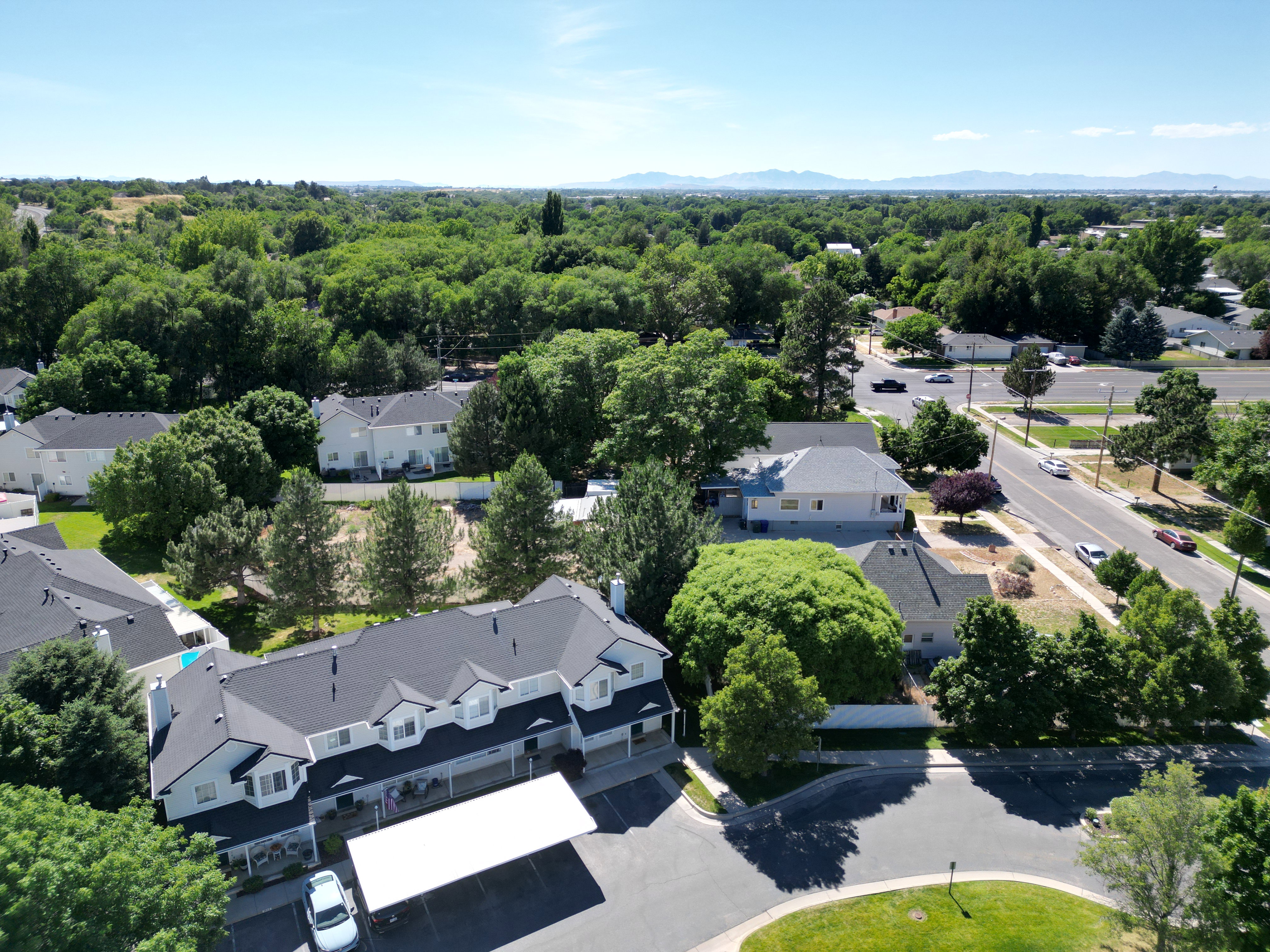 Multi-unit residential property featuring a gray exterior with white trim, dark shingle roofing, and multiple gables