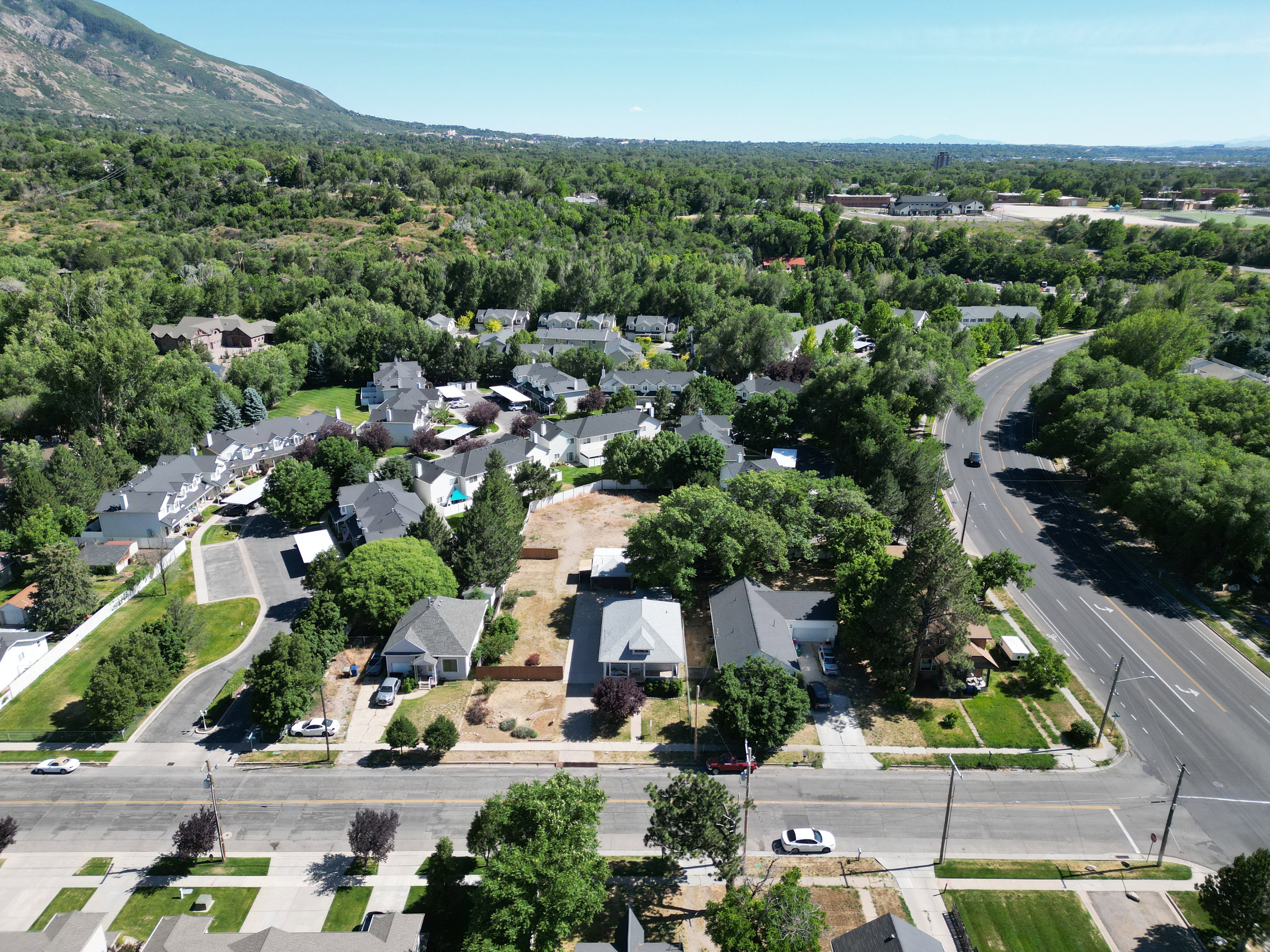 Aerial perspective showcasing a residential property with a surrounding landscape of mature trees and distant mountains