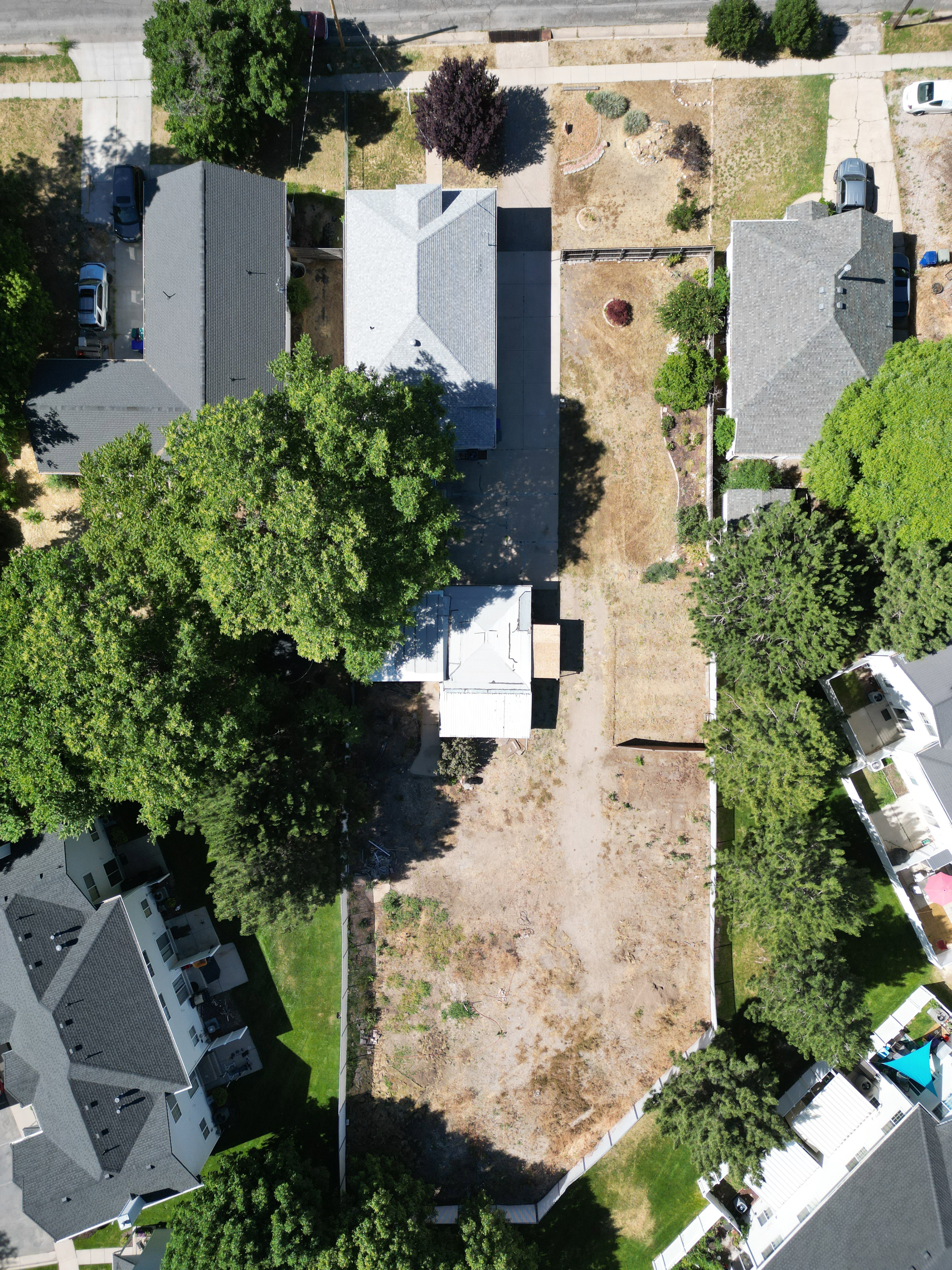 Expansive land parcel featuring existing structures, a substantial undeveloped area, a driveway, and mature trees