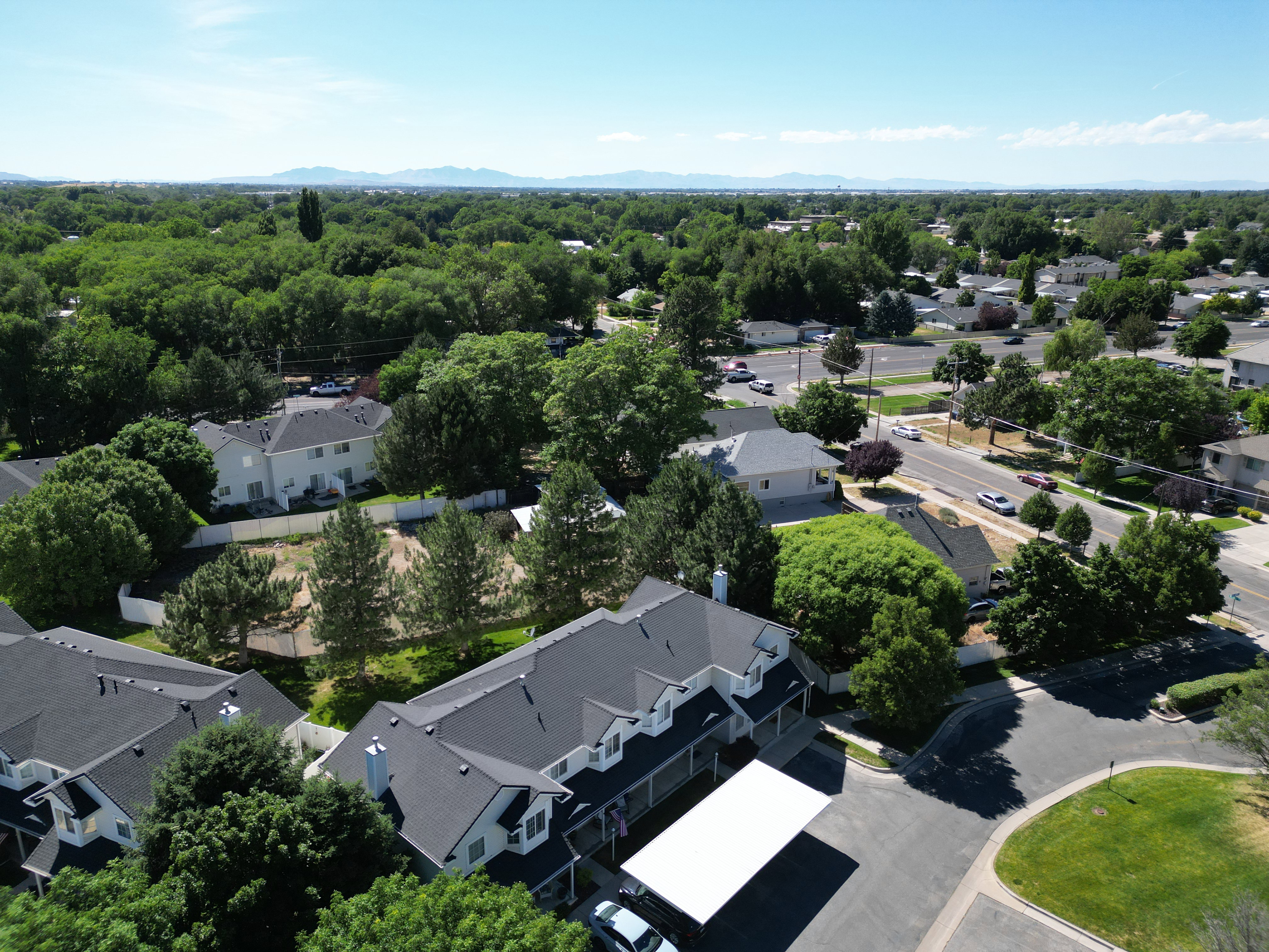 Aerial perspective showcasing a multi-unit property with dark shingle roofing and white siding