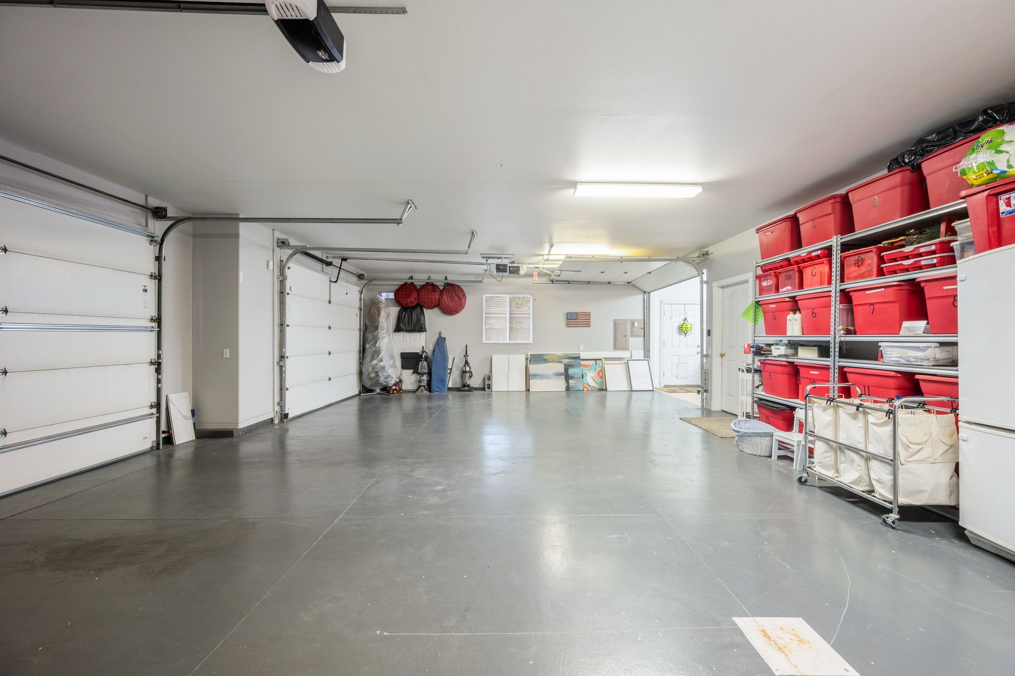 Spacious multi-car garage featuring a concrete floor, white garage doors, and overhead fluorescent lighting
