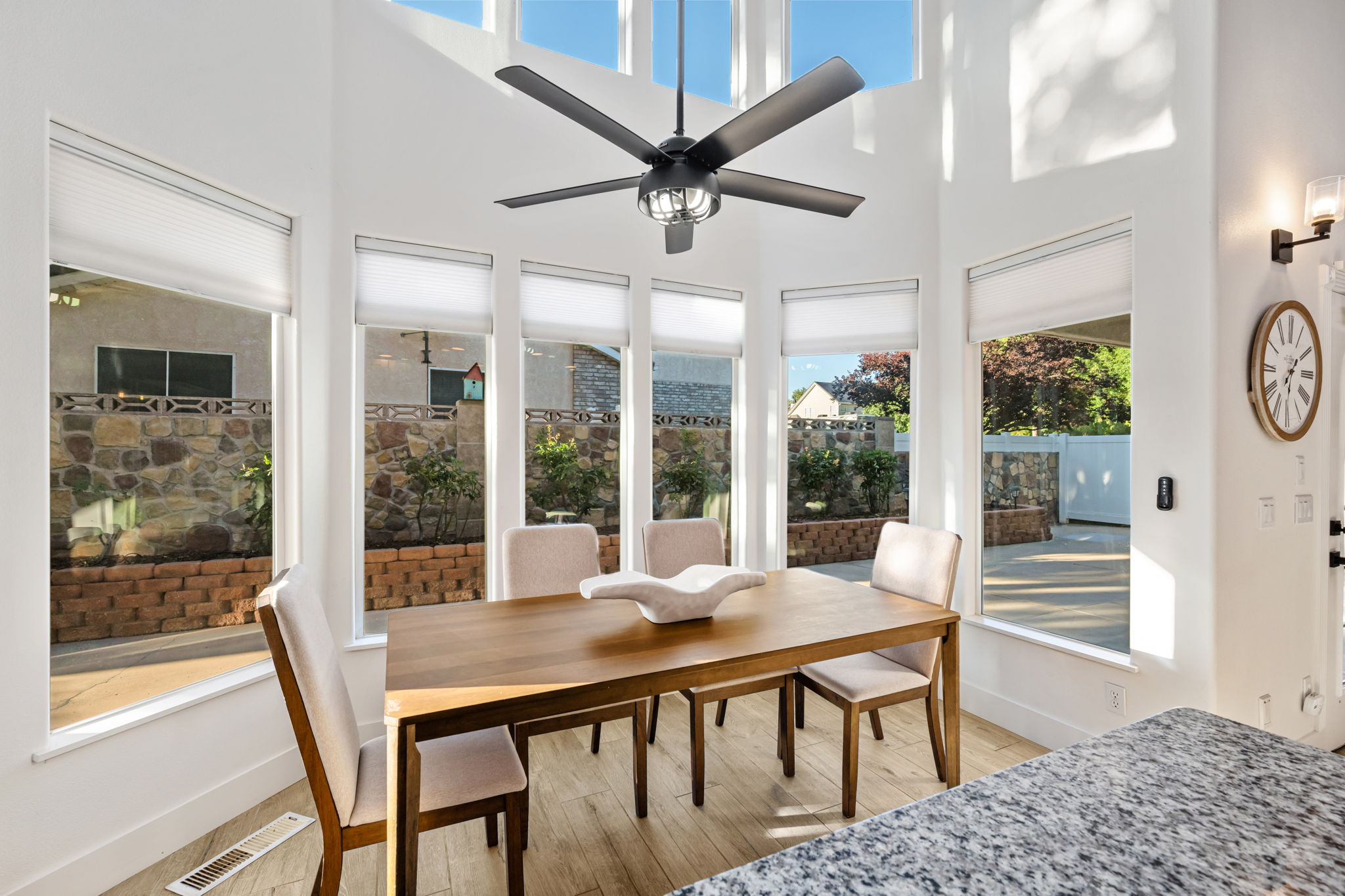 Dining area featuring a vaulted ceiling with a contemporary ceiling fan, expansive windows with window treatments, and light wood-finish flooring