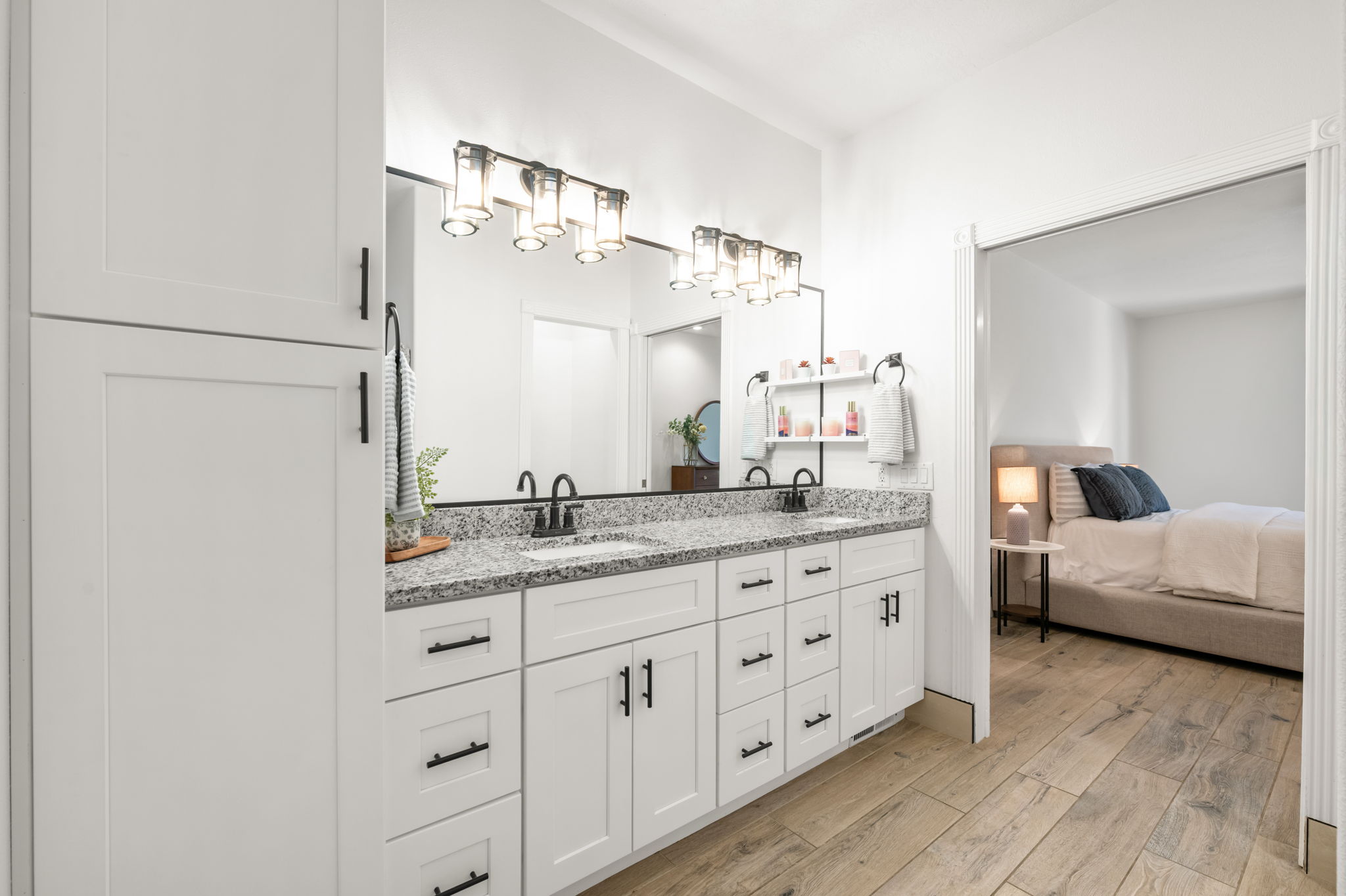 Bathroom with a dual vanity featuring granite countertops, undermount sinks, matte black fixtures, and extensive white shaker-style cabinetry with matte black hardware