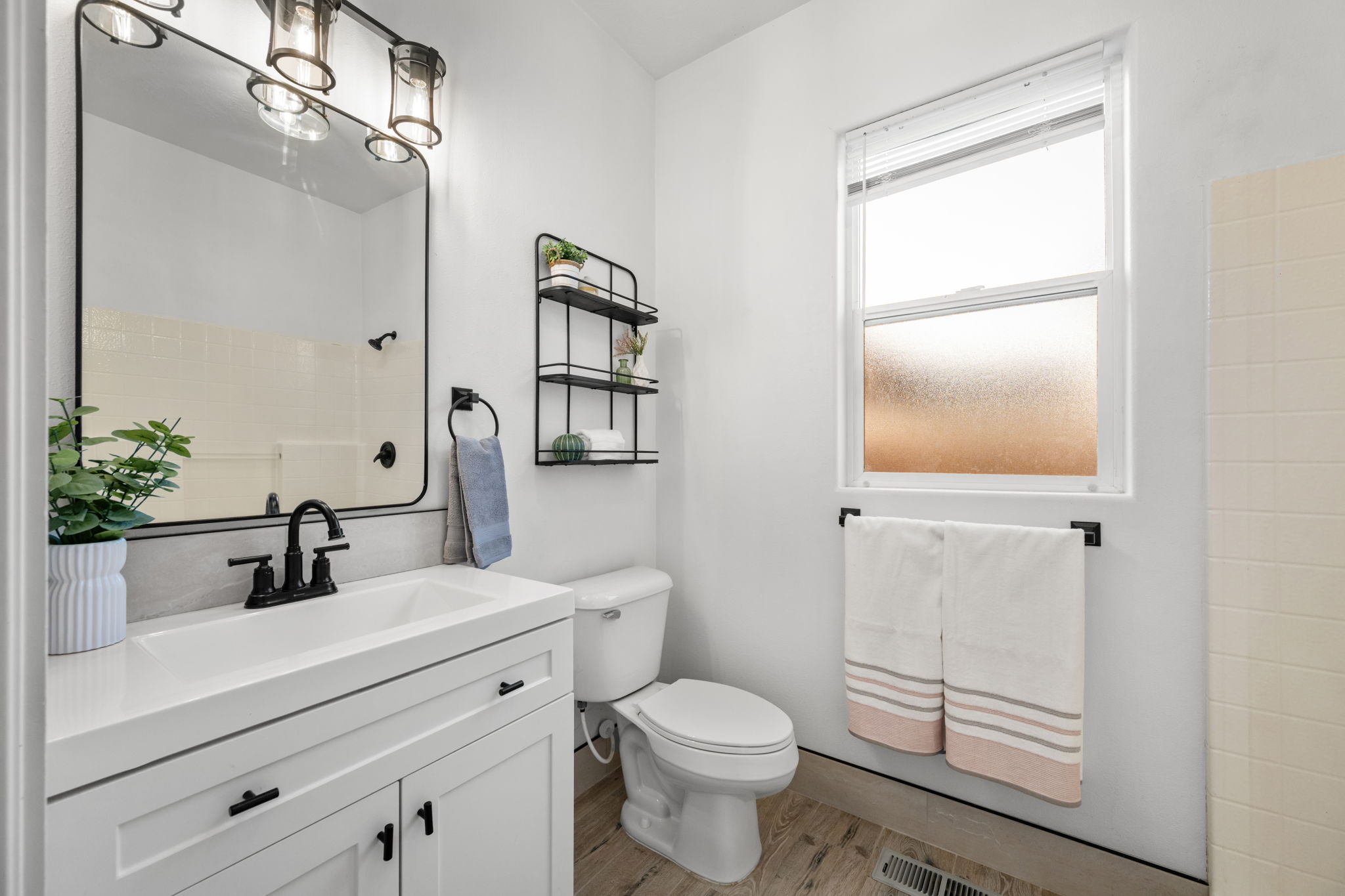 Bathroom featuring a white vanity with integrated sink, black fixtures, and a framed rectangular mirror