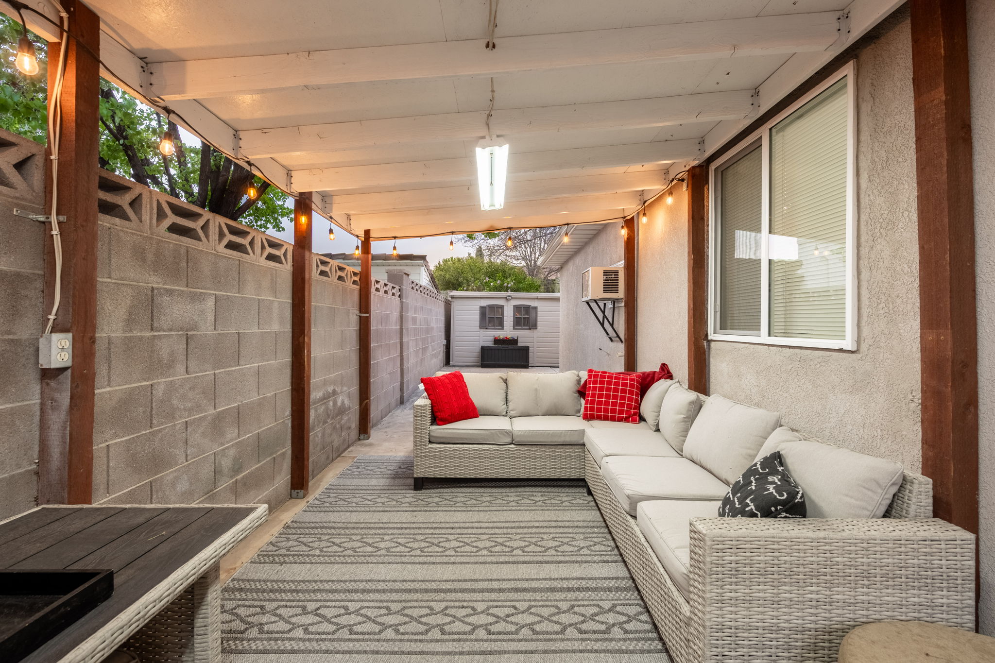 Covered patio space featuring a concrete block wall and a stucco exterior