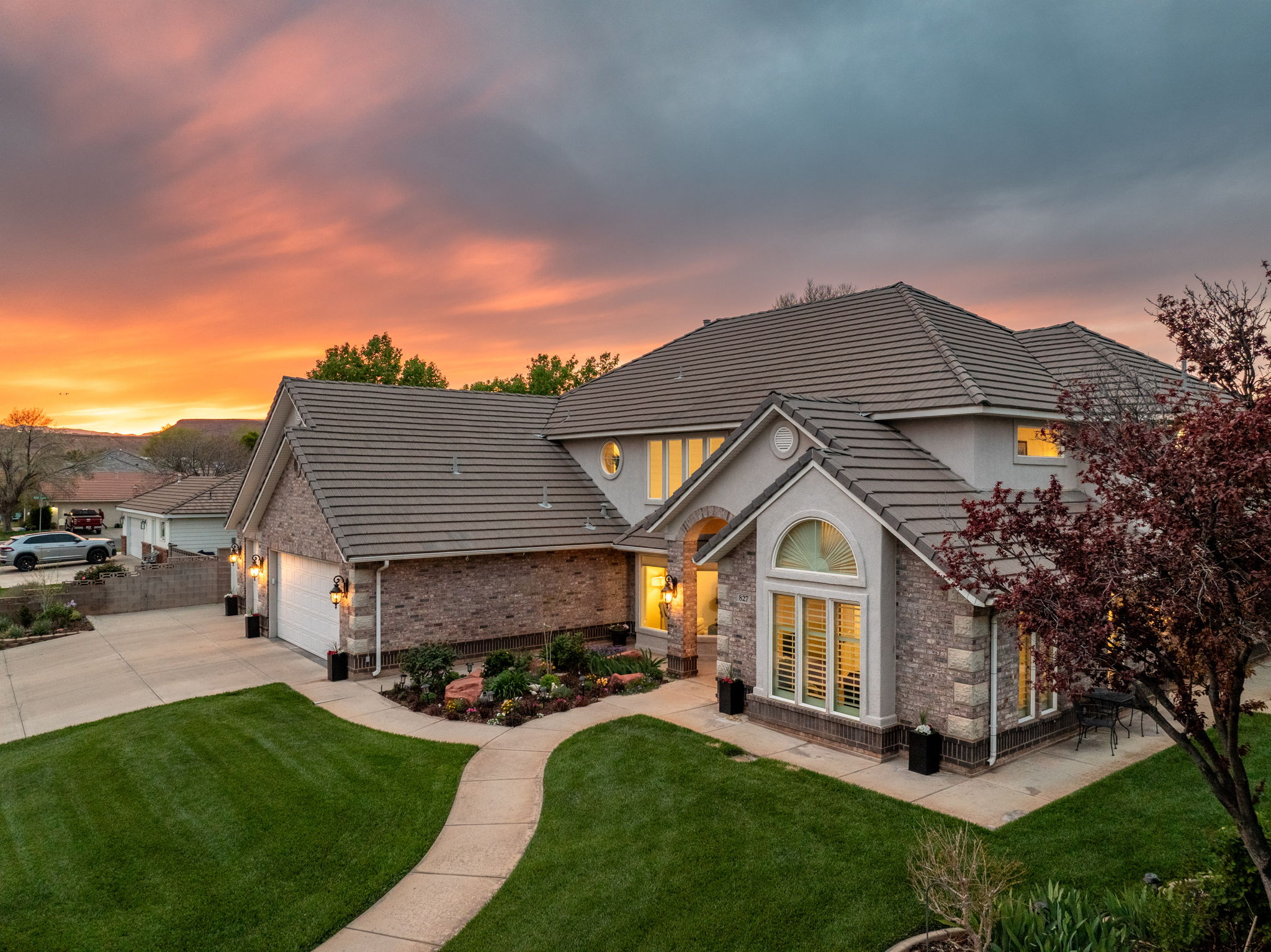 Stucco and brick exterior with a tiled roof, featuring an arched entry and a two-car garage