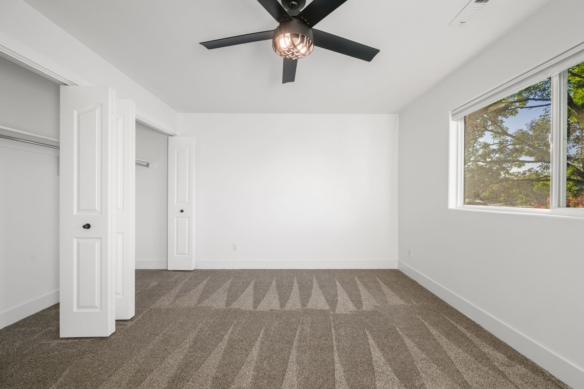 Bedroom featuring patterned carpeting, white walls, and a contemporary ceiling fan with integrated lighting
