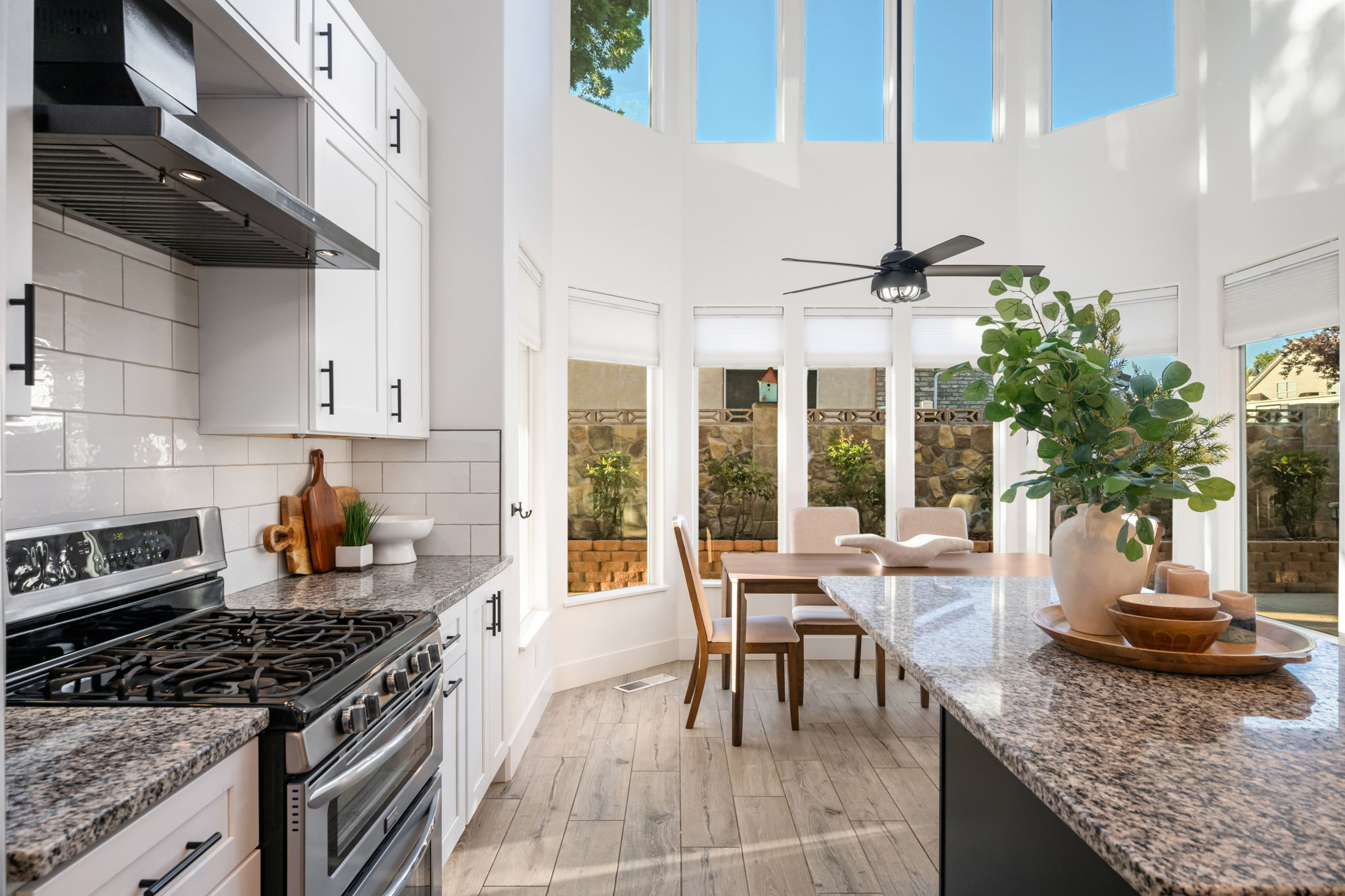 Kitchen featuring wood-finish flooring, white cabinetry with black hardware, stone countertops, and a white subway tile backsplash