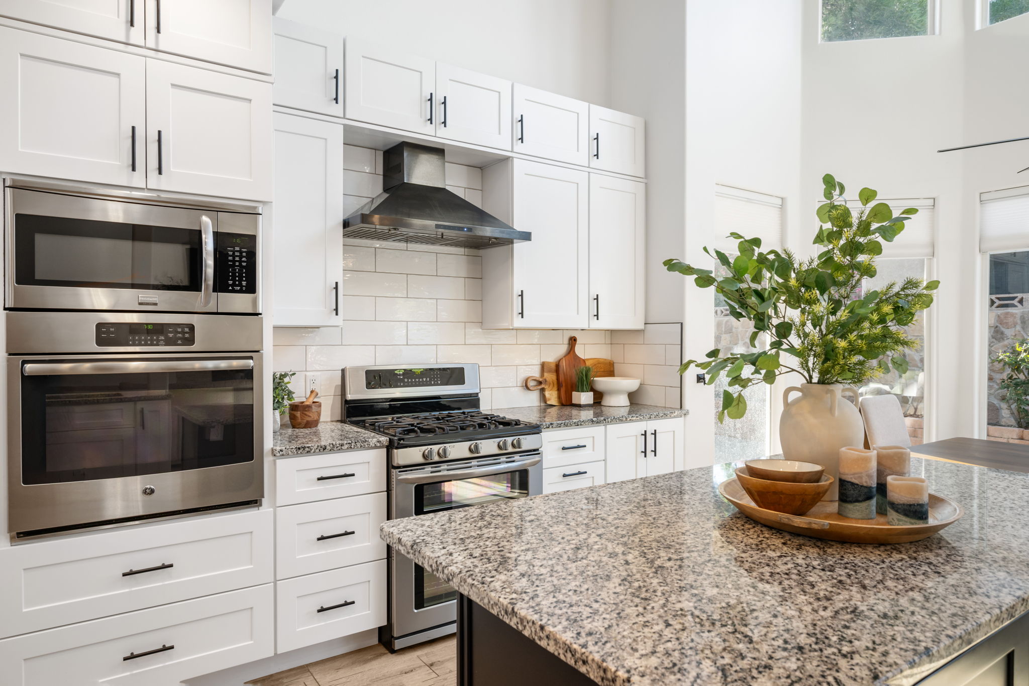 Modern kitchen featuring white shaker cabinetry, stainless steel appliances, a subway tile backsplash, and speckled countertops