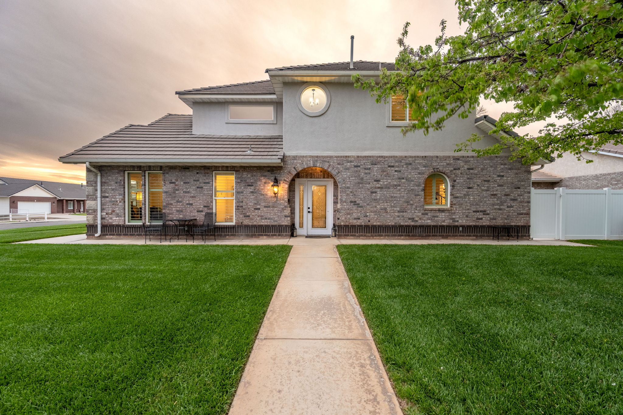 Brick and stucco facade with a covered arched entry, a circular window, and a concrete walkway