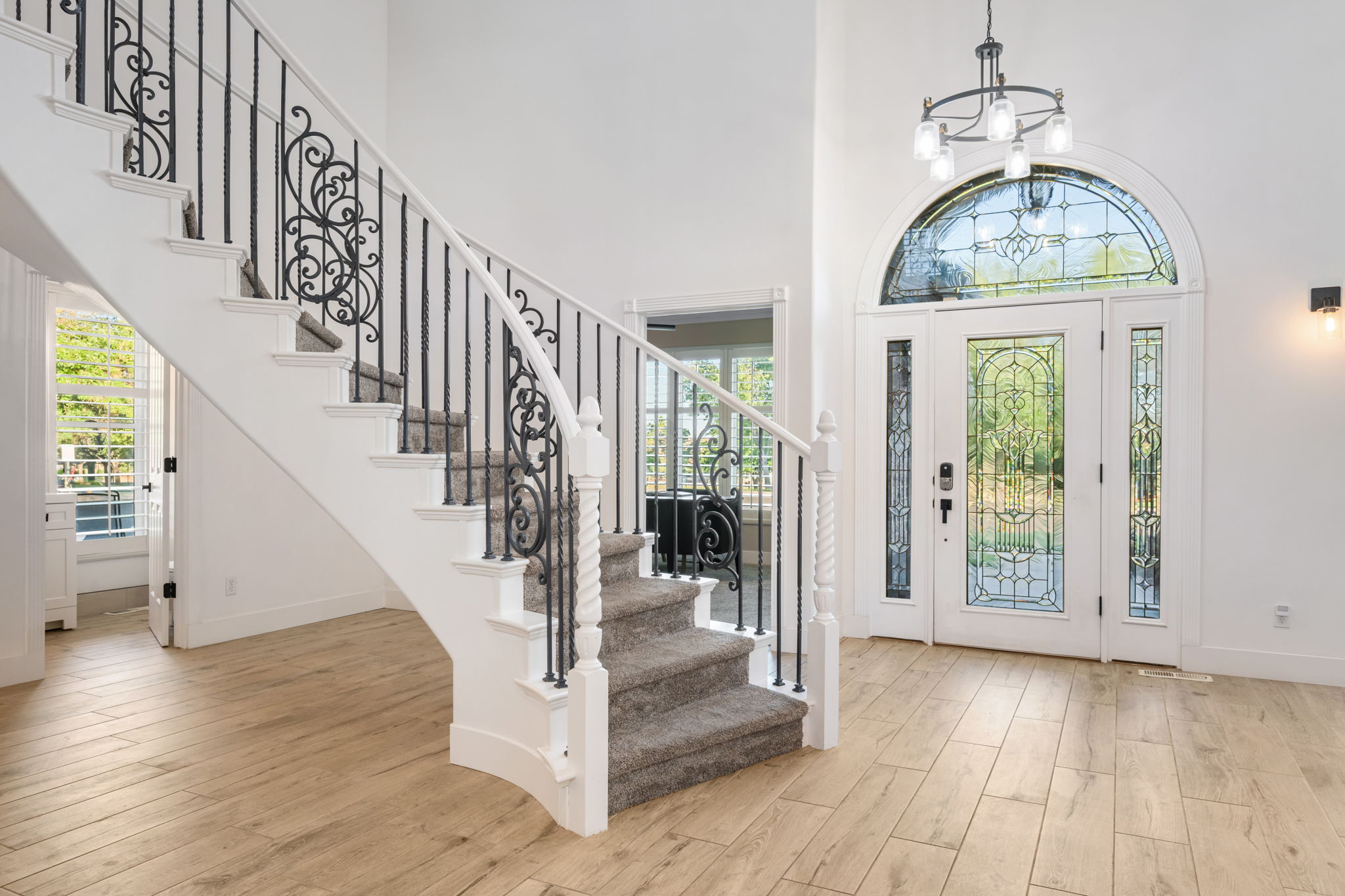 Grand entry featuring a curved staircase with wrought iron balusters and carpeted treads