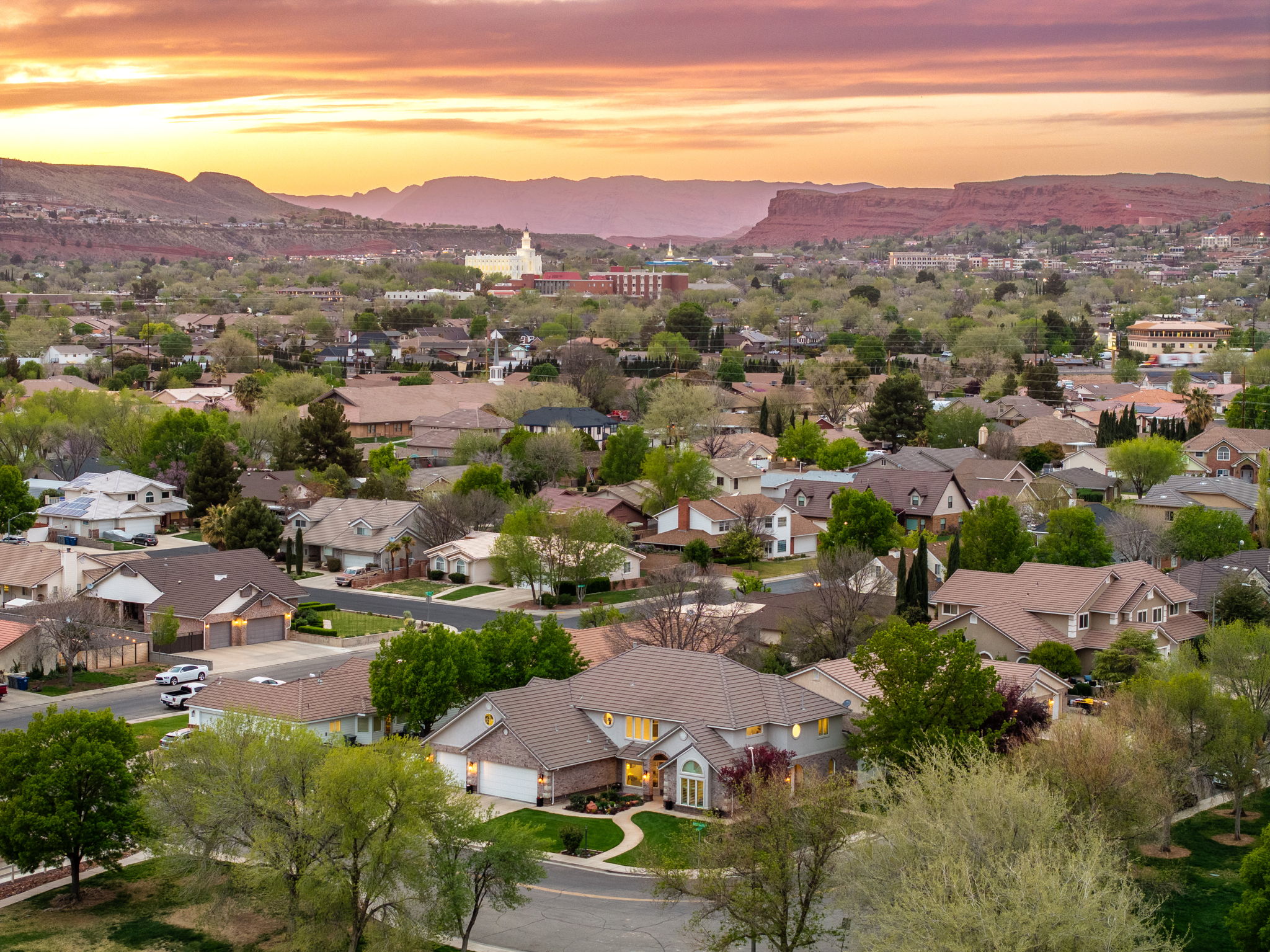 Expansive neighborhood with diverse architectural styles under a dramatic sunset sky