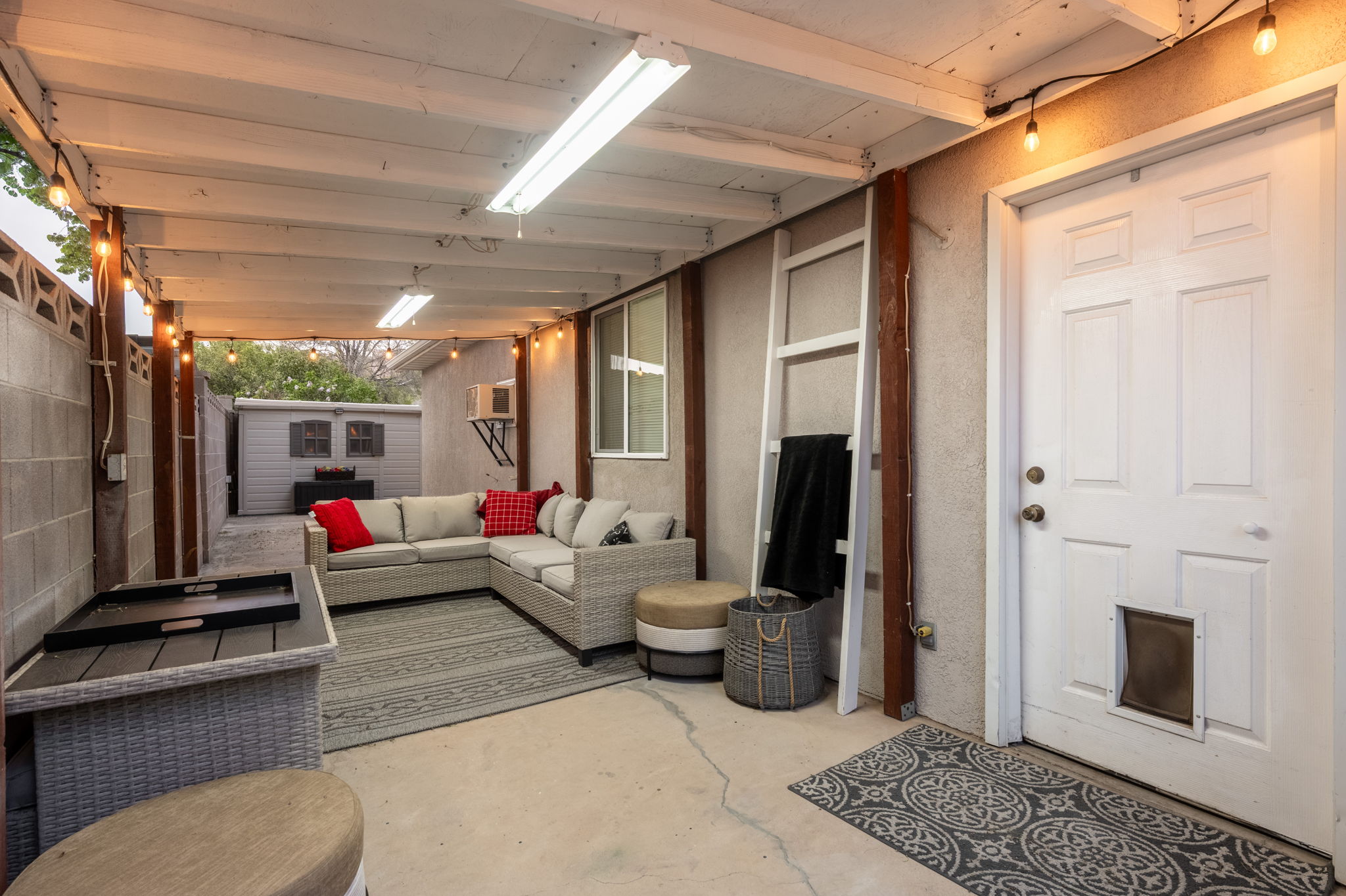 Covered patio featuring an open beam ceiling, string lighting, and concrete flooring