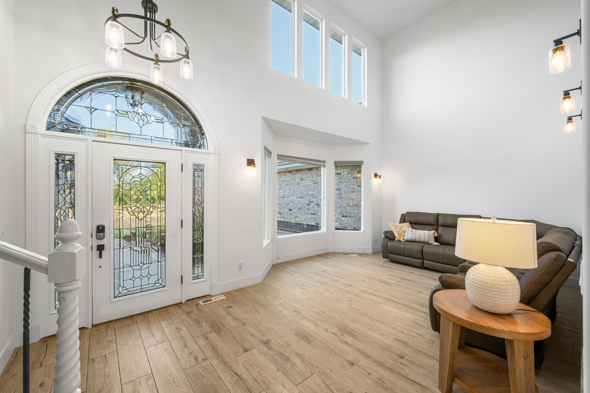 Grand entry featuring a leaded glass front door with a transom window, soaring ceilings, and wood-finish flooring