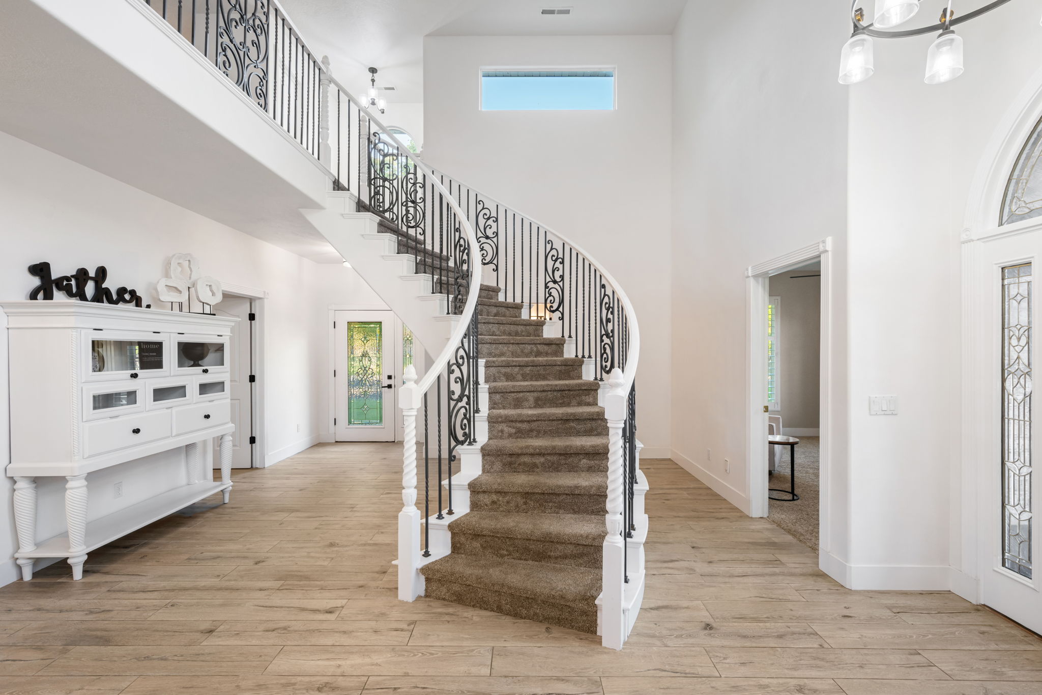 Grand entryway featuring a curved staircase with wrought iron balusters and carpeted treads