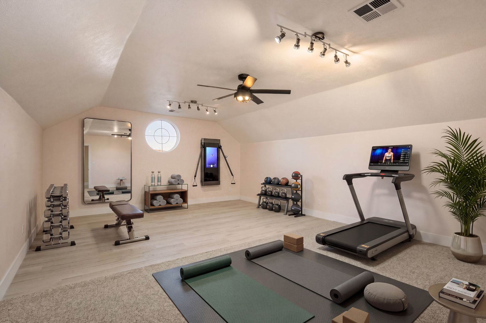Spacious bonus room featuring a circular window, wood-finish flooring, and a ceiling fan
