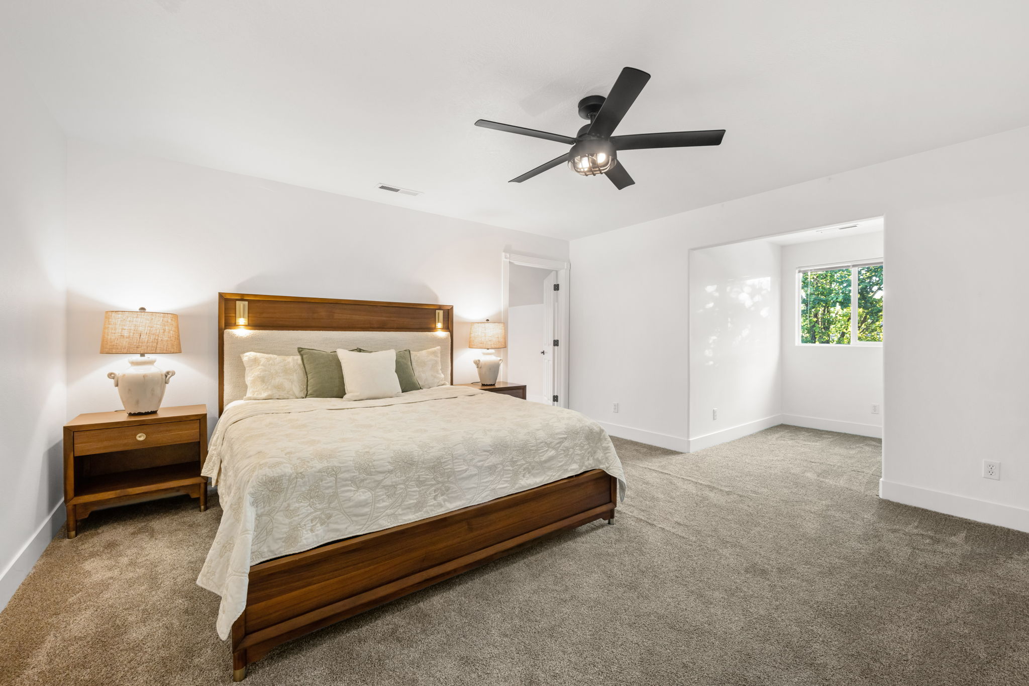 Spacious bedroom featuring light-colored walls and plush carpeting