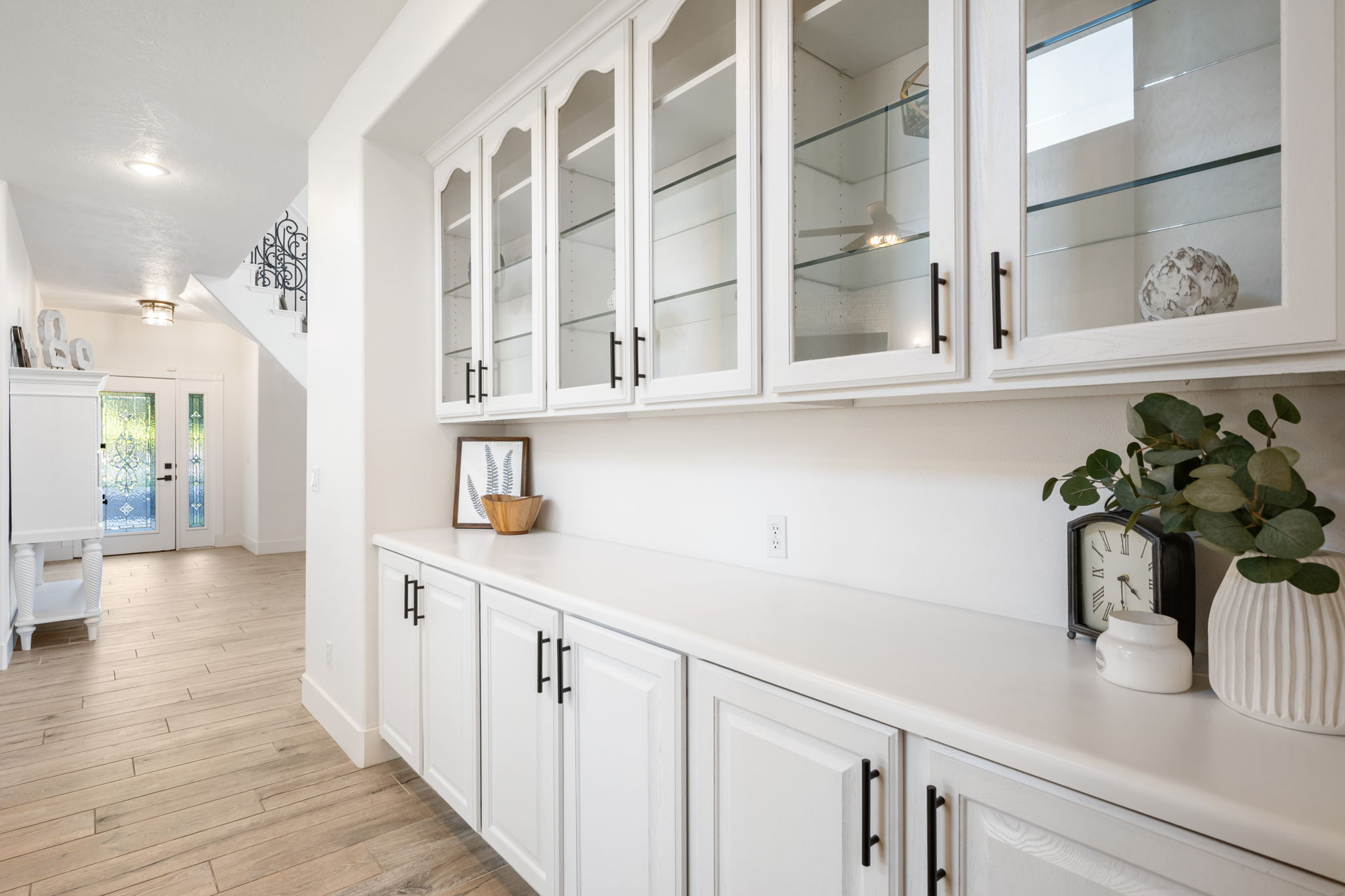 Built-in white cabinetry with glass-front uppers and black hardware