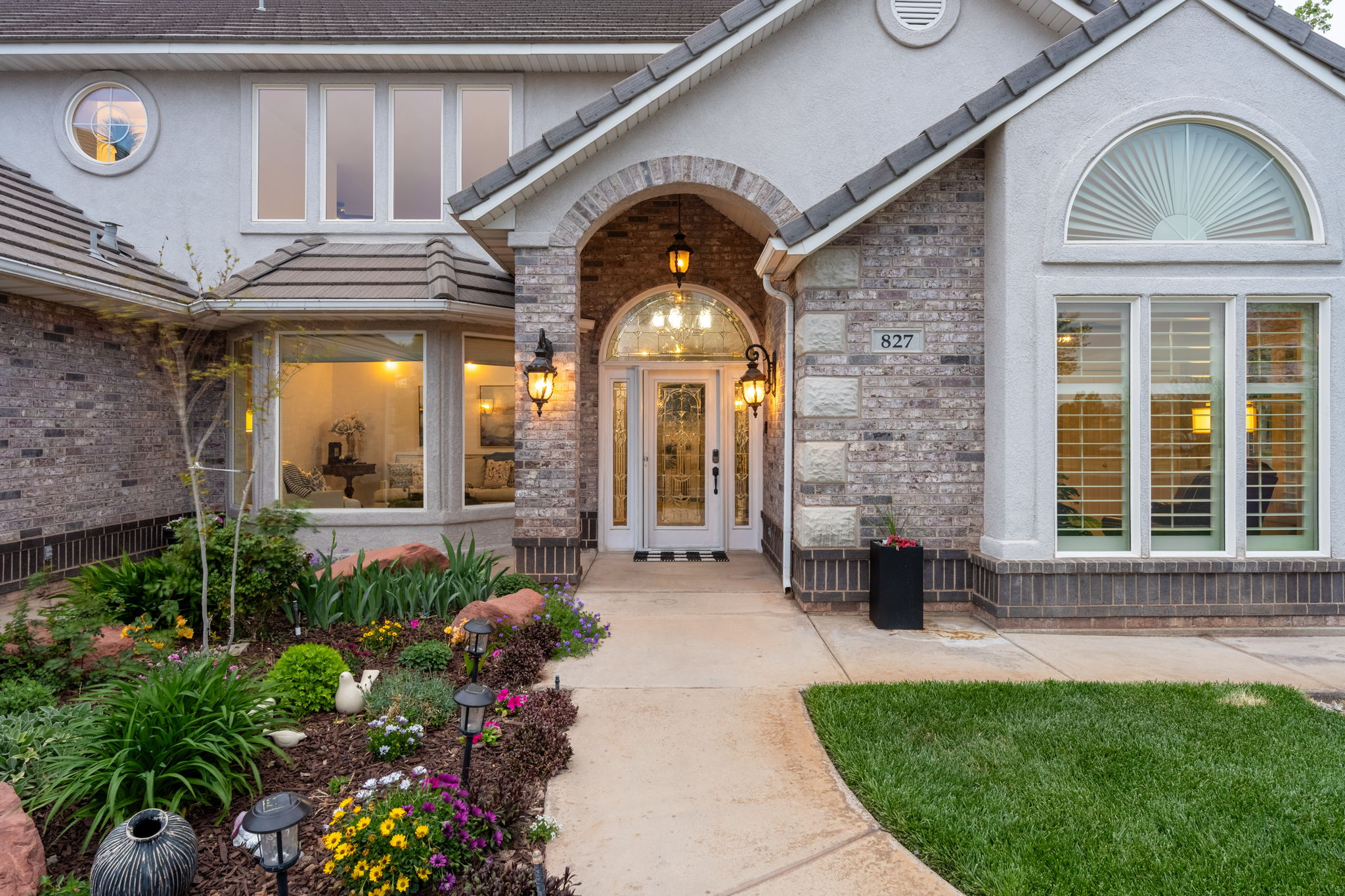 Inviting brick and stucco exterior featuring an arched entry, a decorative glass front door, and multiple large windows with architectural detailing