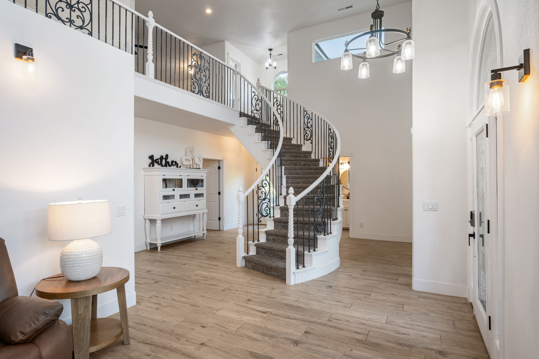 Grand foyer featuring a curved staircase with wrought iron balusters and carpeted treads