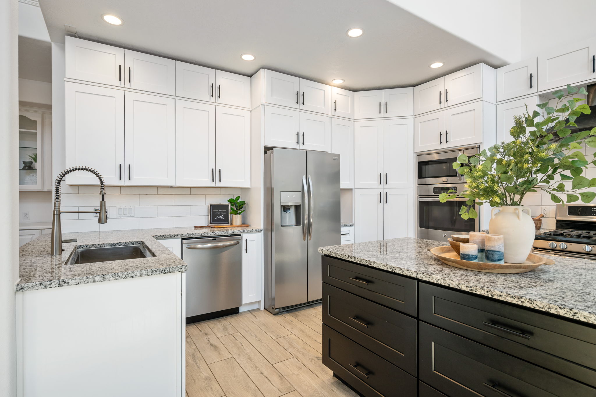Modern kitchen featuring white shaker cabinetry, stainless steel appliances, speckled stone countertops, a subway tile backsplash, and wood-finish flooring
