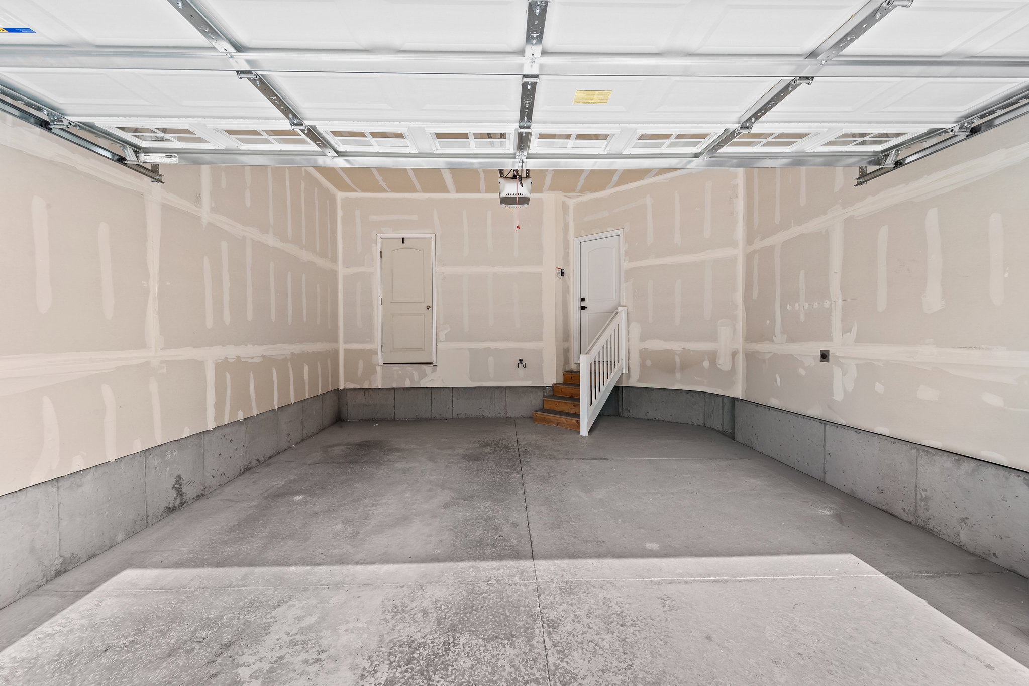 Spacious garage featuring concrete flooring, unpainted drywall, and an overhead garage door system