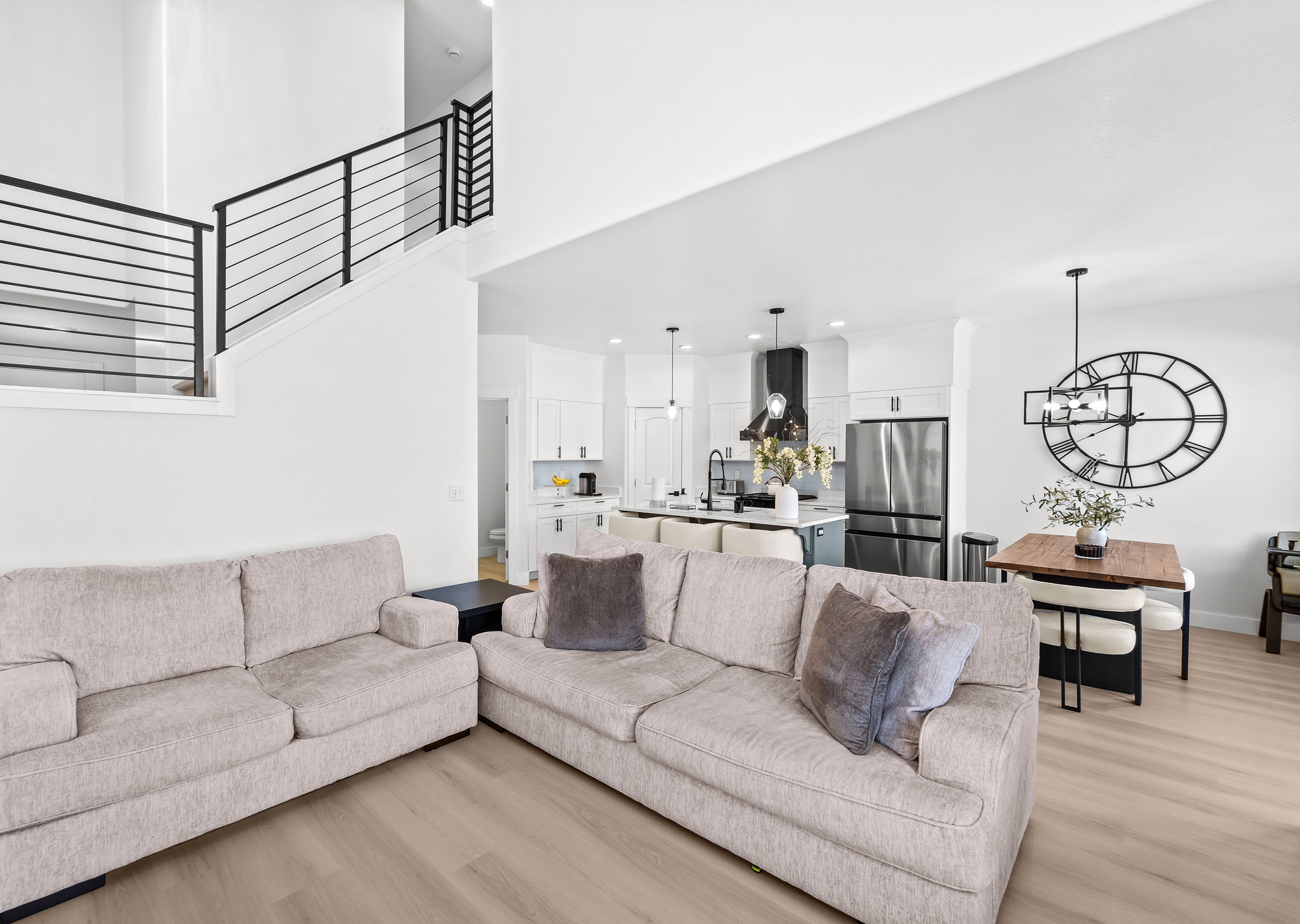 Open-concept living space featuring high ceilings, wood-finish flooring, and a modern staircase with black metal railings