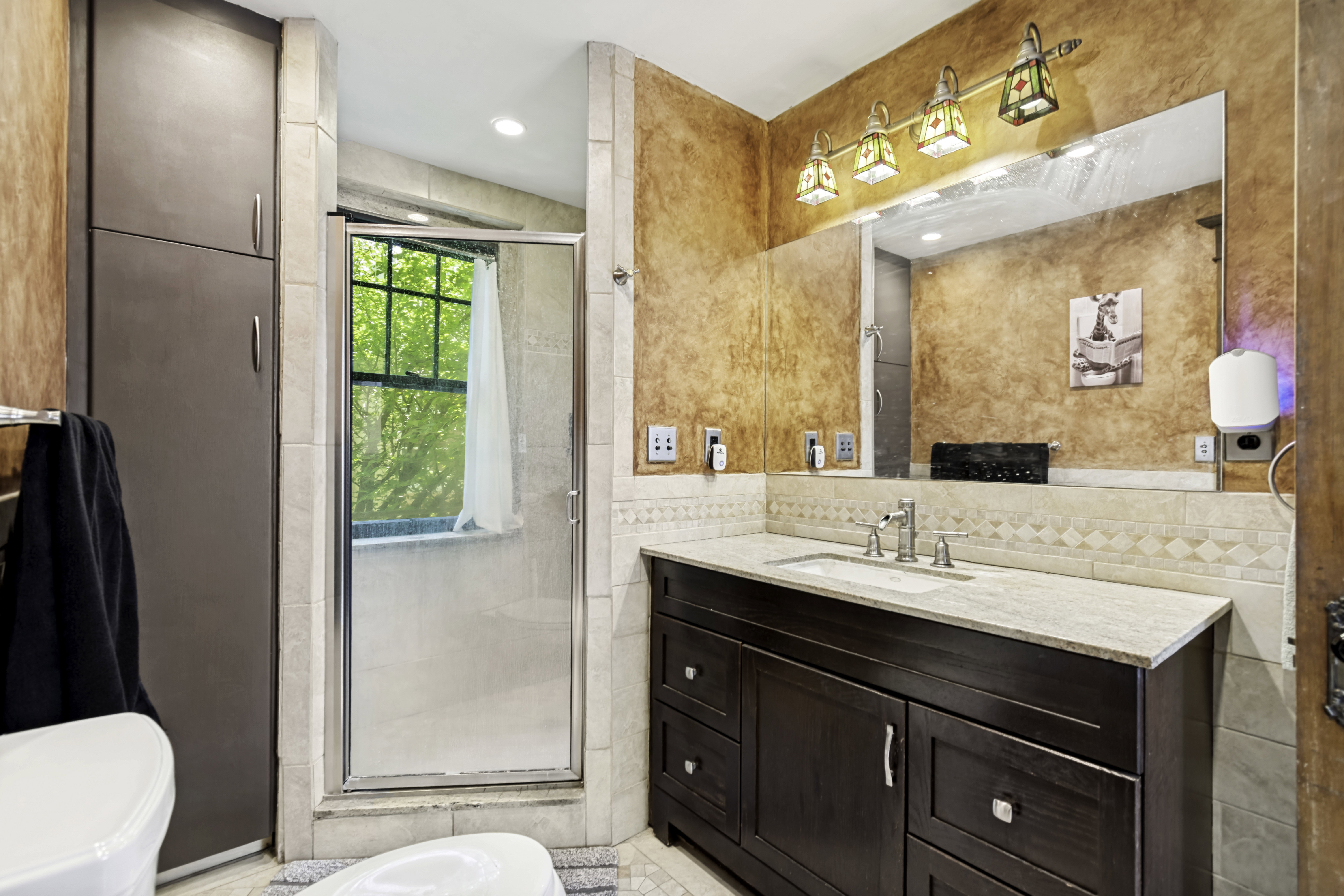 Vanity featuring a light-colored countertop, an undermount sink, and a dark wood-finish cabinet with multiple drawers and doors