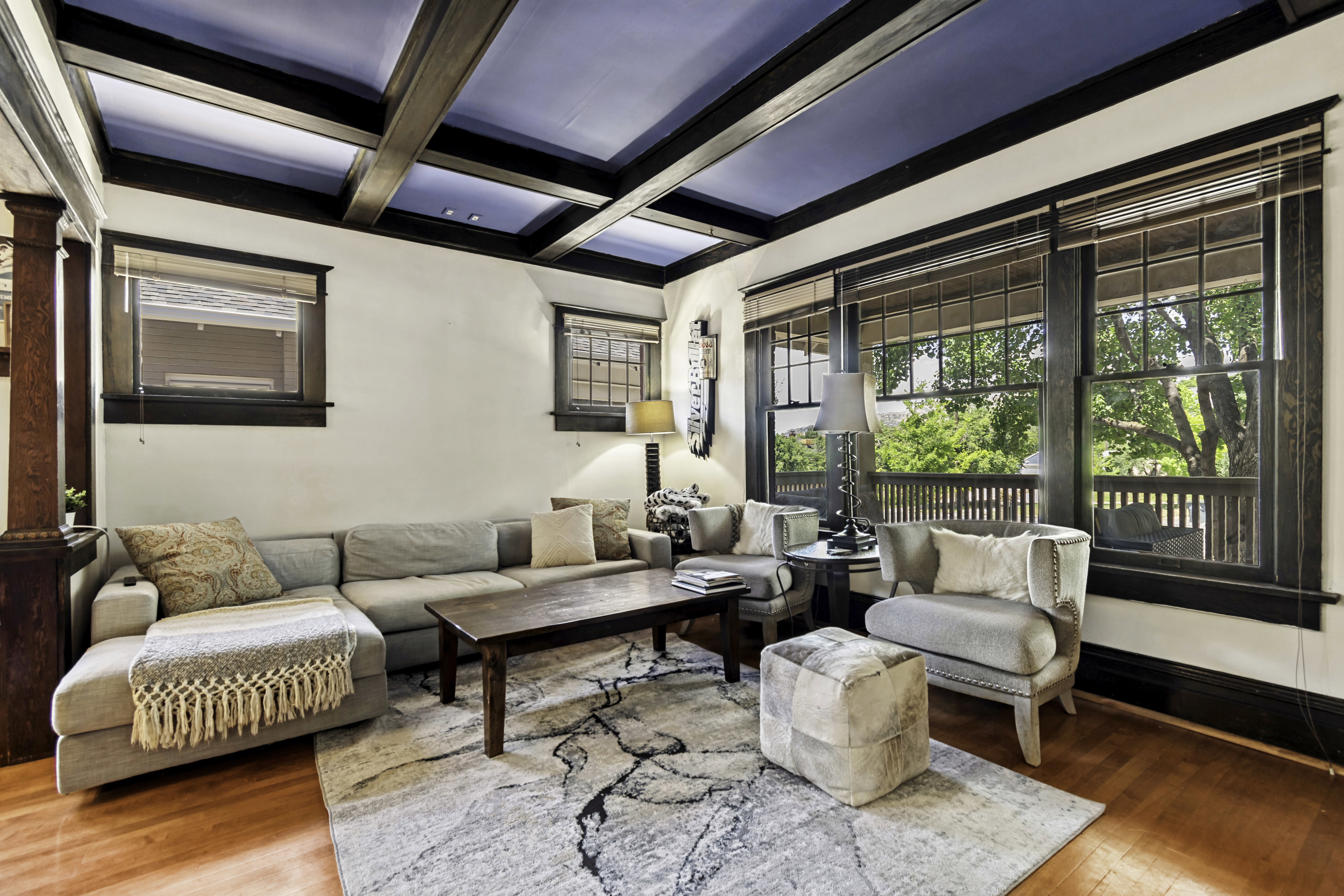 Living area featuring a coffered ceiling with a blue inset, wood-finish flooring, and expansive windows