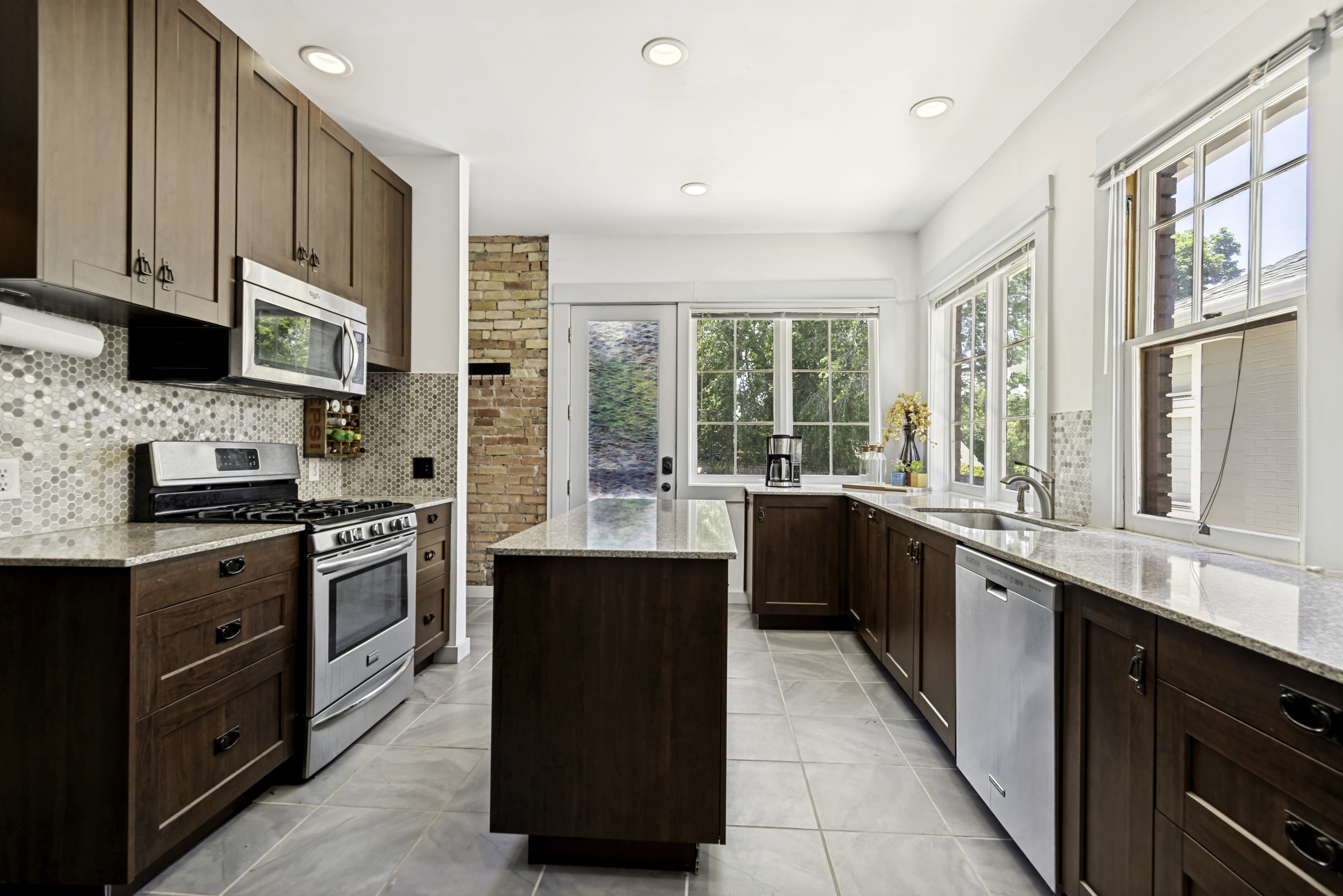 Kitchen featuring dark wood cabinetry, light-colored granite countertops, and stainless steel appliances