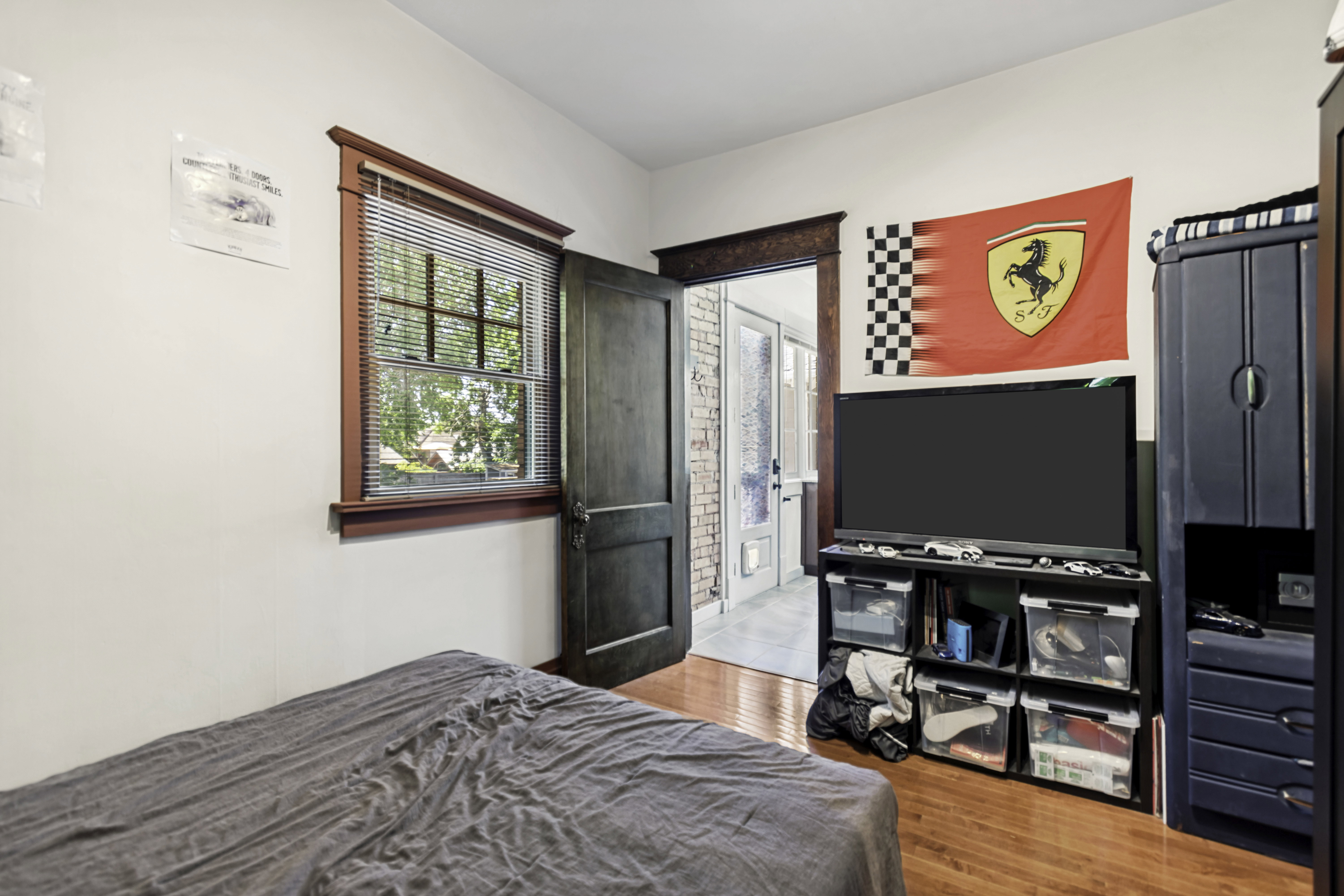 Interior space featuring wood-finish flooring, white painted walls, and a window with blinds