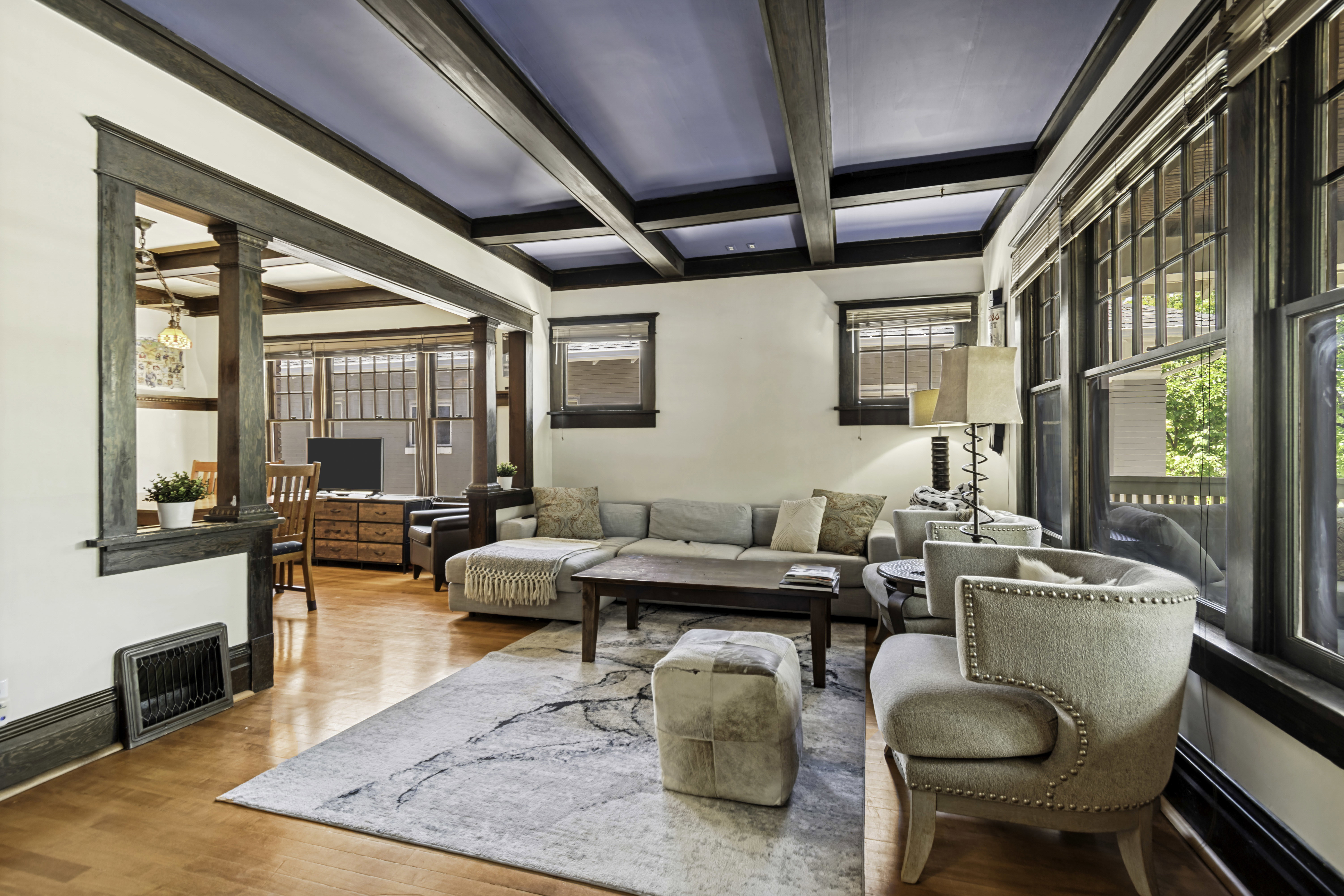 Living area featuring wood-finish flooring, a coffered ceiling with dark beams, and prominent windows