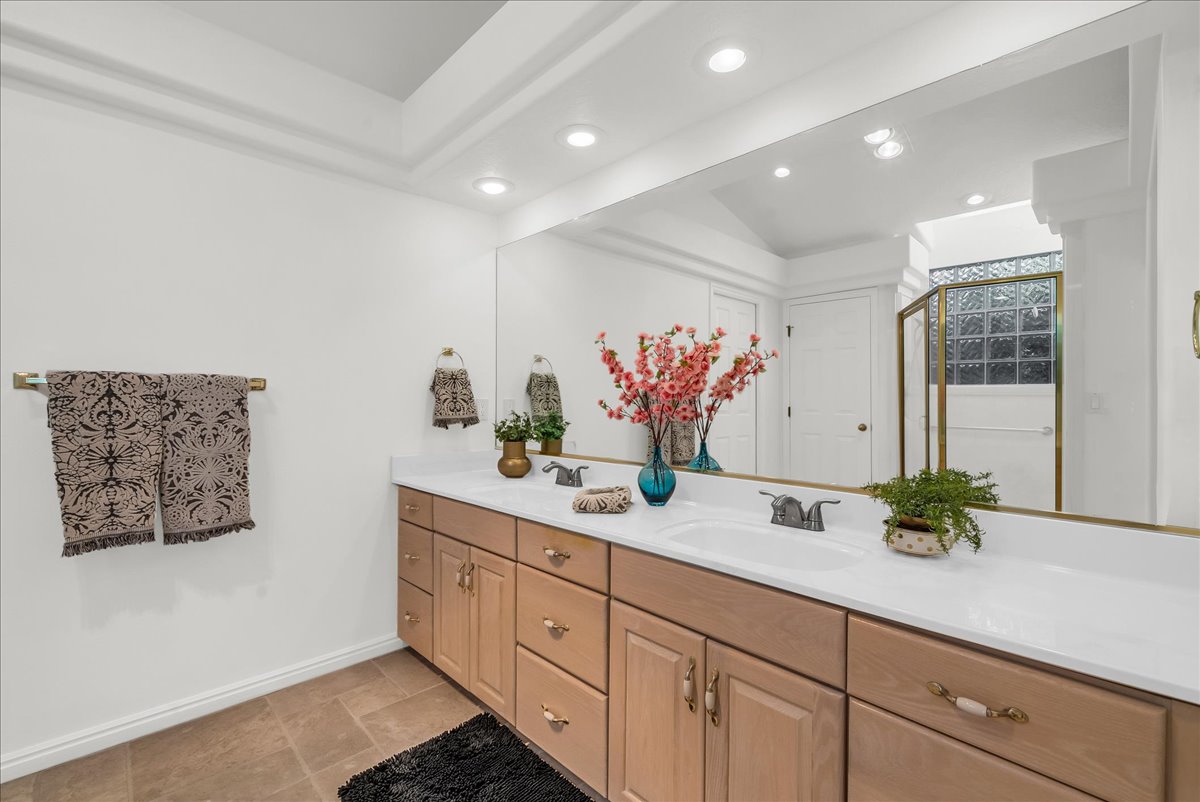 Double vanity featuring light wood-finish cabinetry, integrated sinks, and polished brass fixtures
