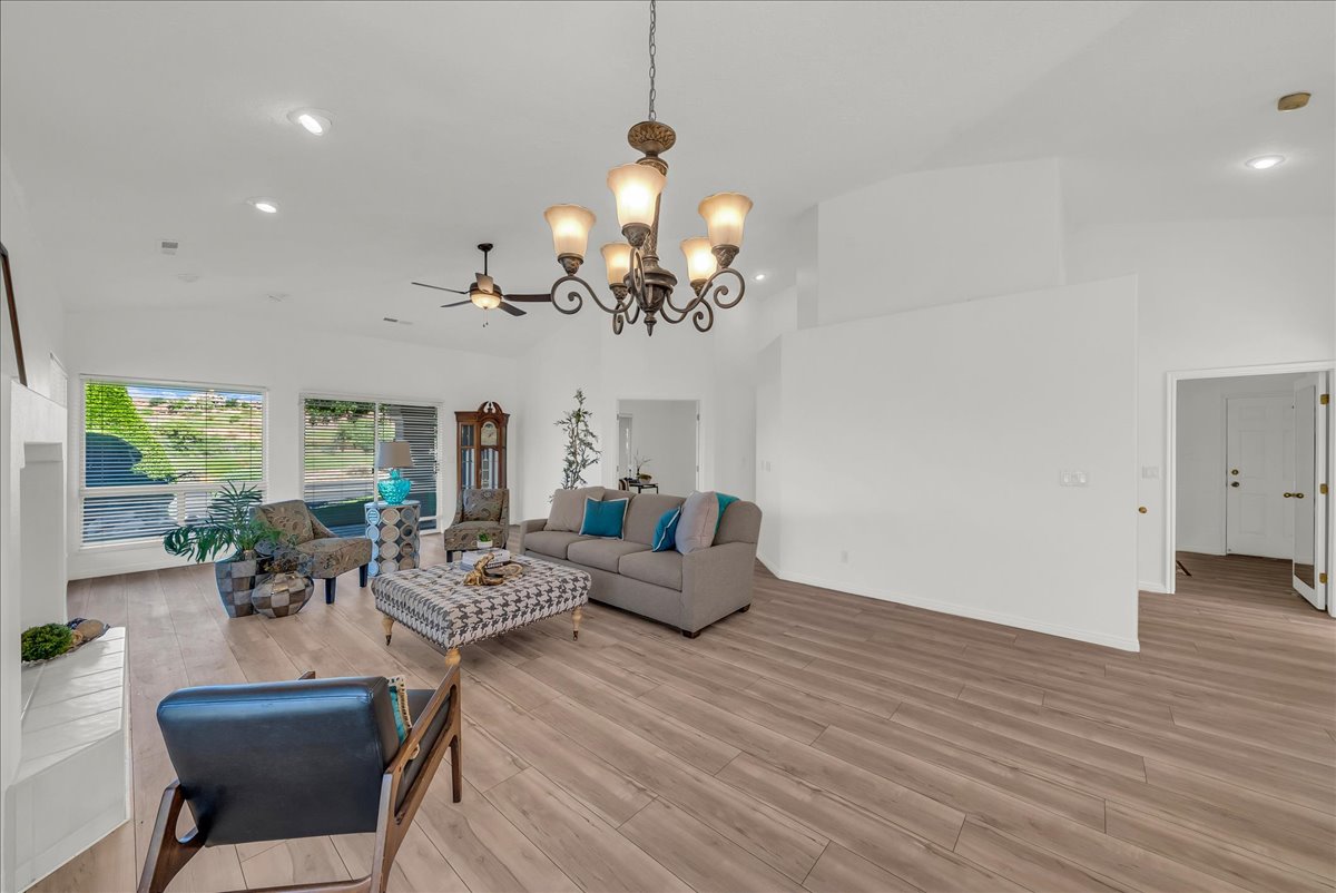 Spacious living area featuring vaulted ceilings, wood-finish flooring, recessed lighting, a ceiling fan, and large windows offering abundant natural light