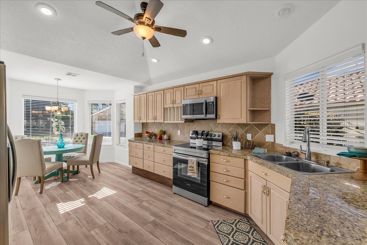 Kitchen and dining area featuring wood-finish flooring, light wood cabinetry, and granite-style countertops